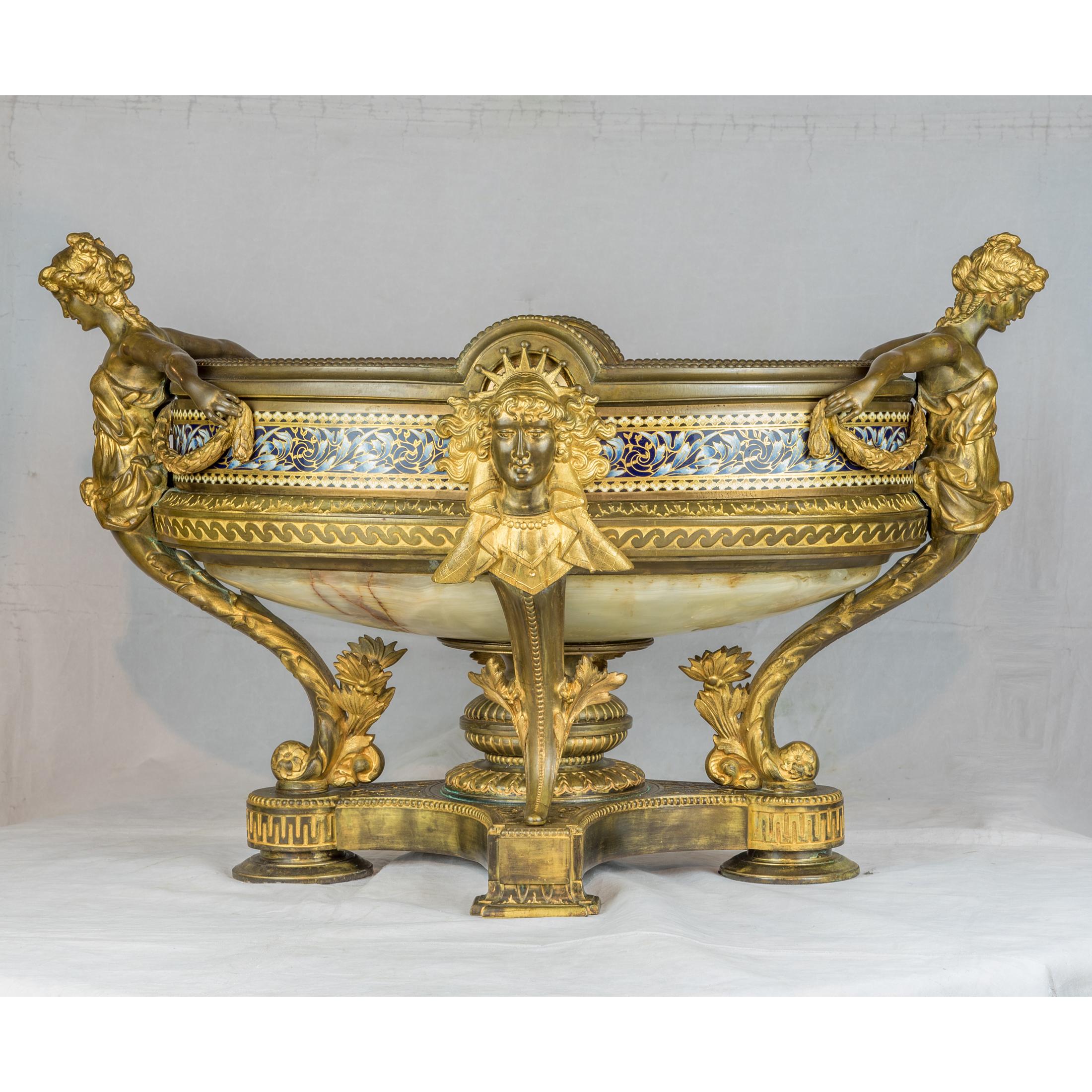 A very fine quality renaissance revival gilt-bronze and champlevé planter, with oval bowl and caryatid handles, a regal mask head to either side and with central enameled band, flanked by a pair of Gilt-Bronze onyx and Cloisonné Enamel Covered Urns