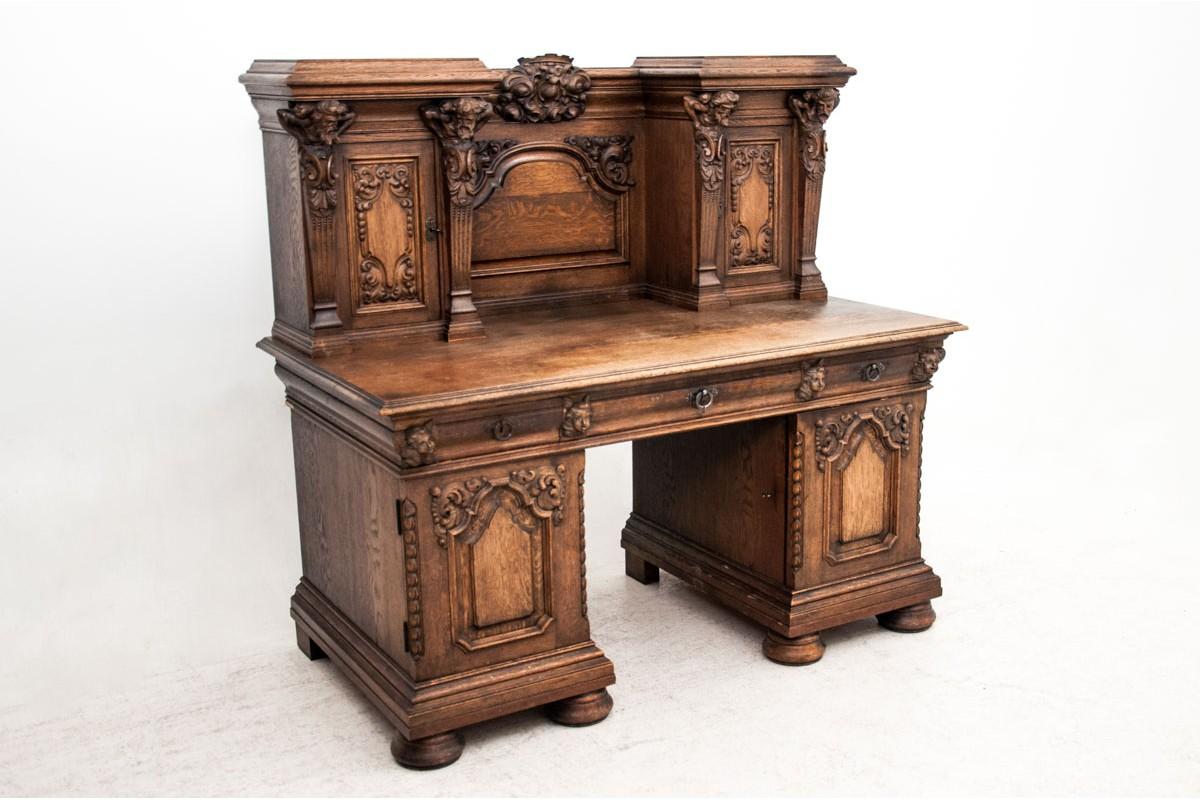 An antique, massive desk with an extension was made of oakwood at the end of the 19th century. The furniture made in the Renaissance style has side cabinets and three roomy drawers, plus a practical extension. Door panels heavily decorated with