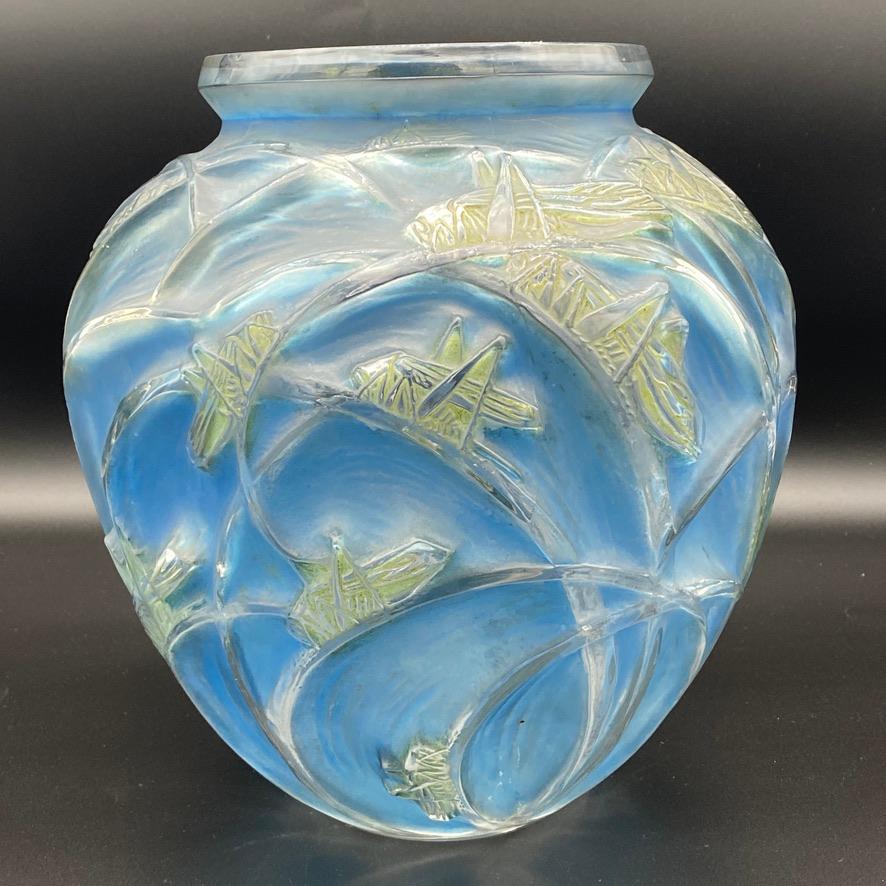The criquet vase as an early creation of R.Lalique as glass maker.

It is still strongly influenced by the Art Nouveau style observing the different positions of the criquets on the branches .

The double patina which is blue on the leaves and light