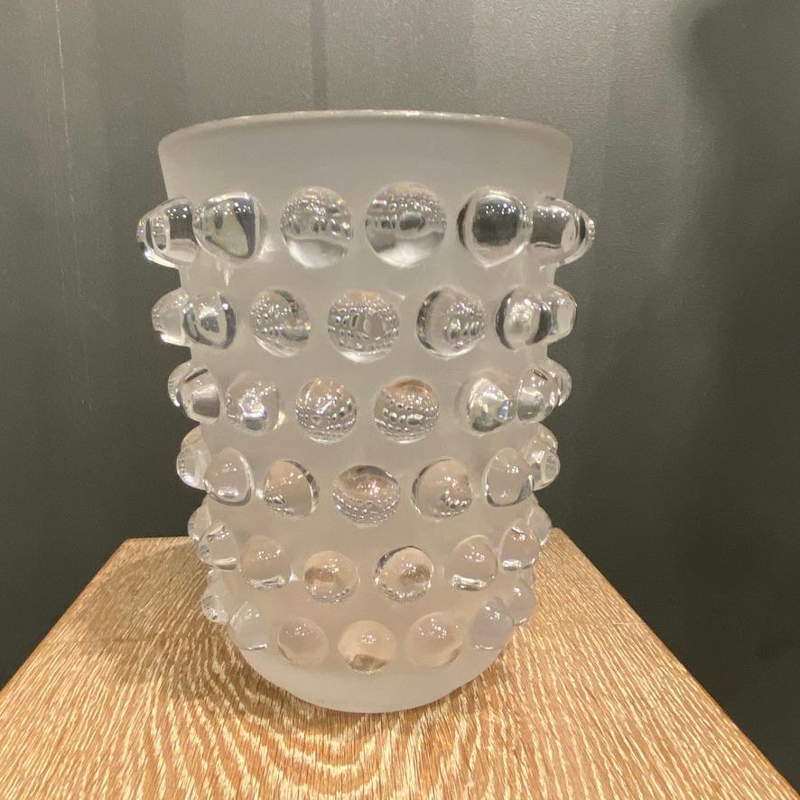 Die Vase Mossi wurde 1933 von R. Lalique aus weißem Glas geschaffen.

Es ist nach wie vor ein Bestseller, denn das schlichte Design ist eine perfekte Illustration der Art-Déco-Inspiration.
Die polierten Punkte heben sich auf dem stark gefrosteten