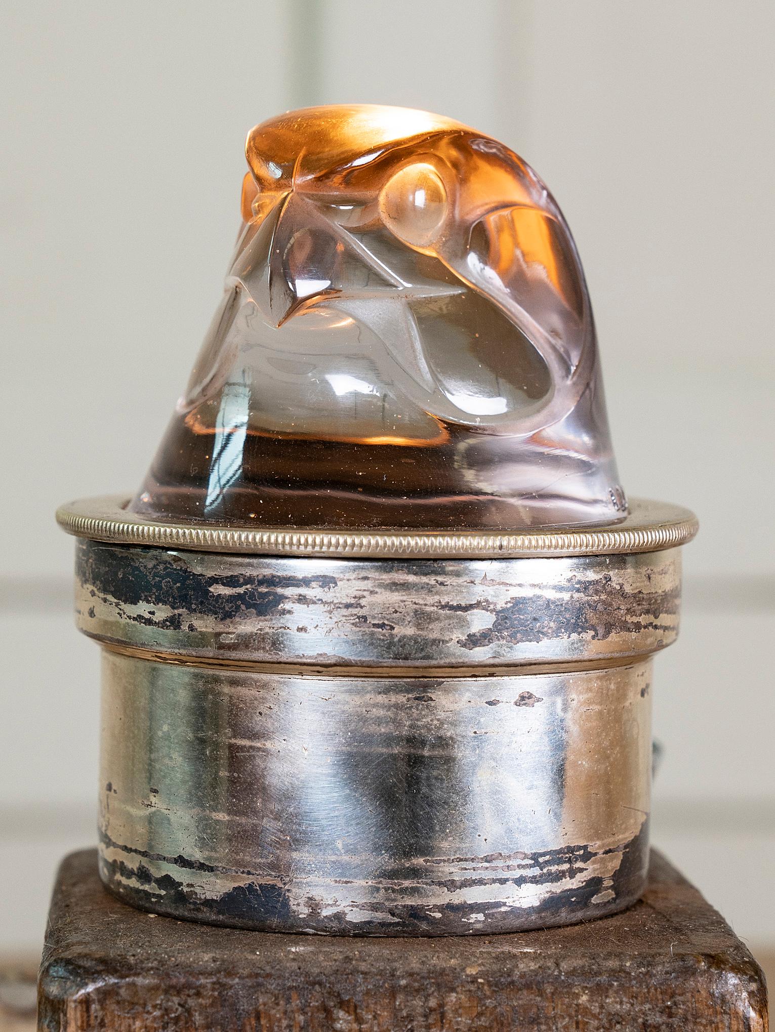 A illuminating glass Eagle head radiator cap car mascot.

Lalique commissioned Breves Gallery in Knightsbridge to mount his mascots and hood ornaments and then retail them to the British public.
The glass mascots were mounted in nickel plated