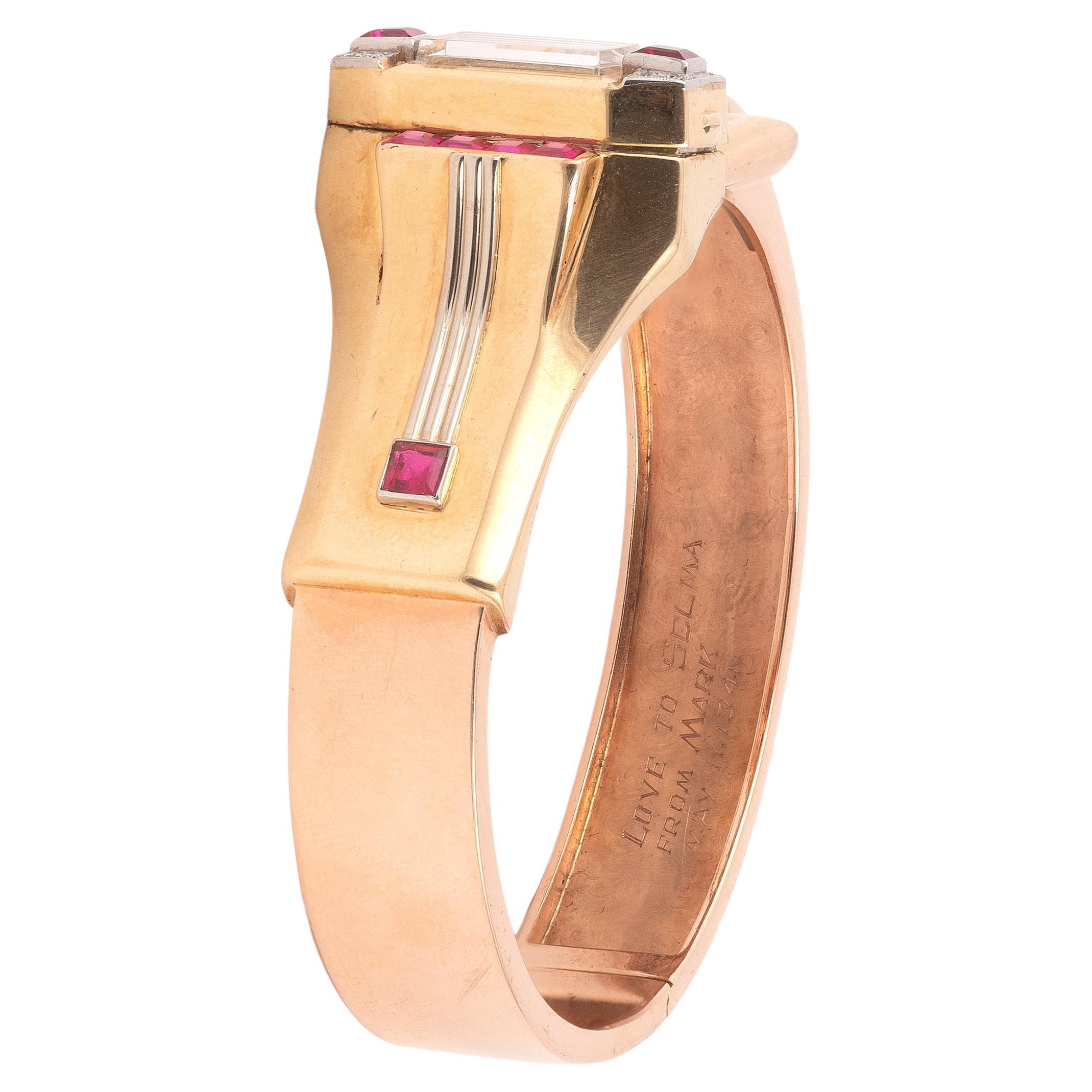 The hinged fluted bangle bracelet detailed to the center with a tapered row of rectangular buff-top rubies, centering a watch with rectangular dial and black Arabic numerals, accented with round brilliant-cut diamond and calibré-cut ruby terminals;