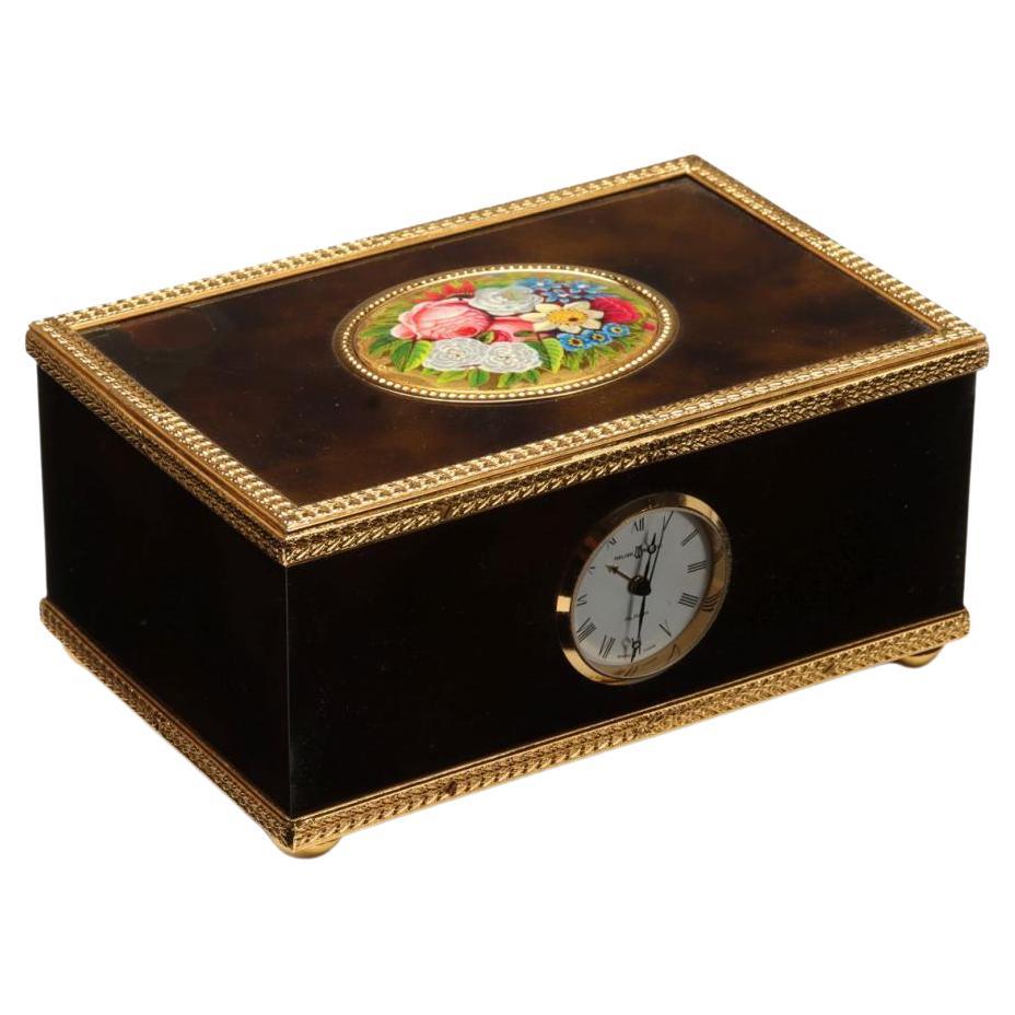 The box with brown enamel exterior and singing bird as shown in good working order. The top left corner has enamel loss as shown in the second image.

Measures 2.25 x 4.75 x 3 inches.
The clock winds and is presumed to keep time. The bird lists