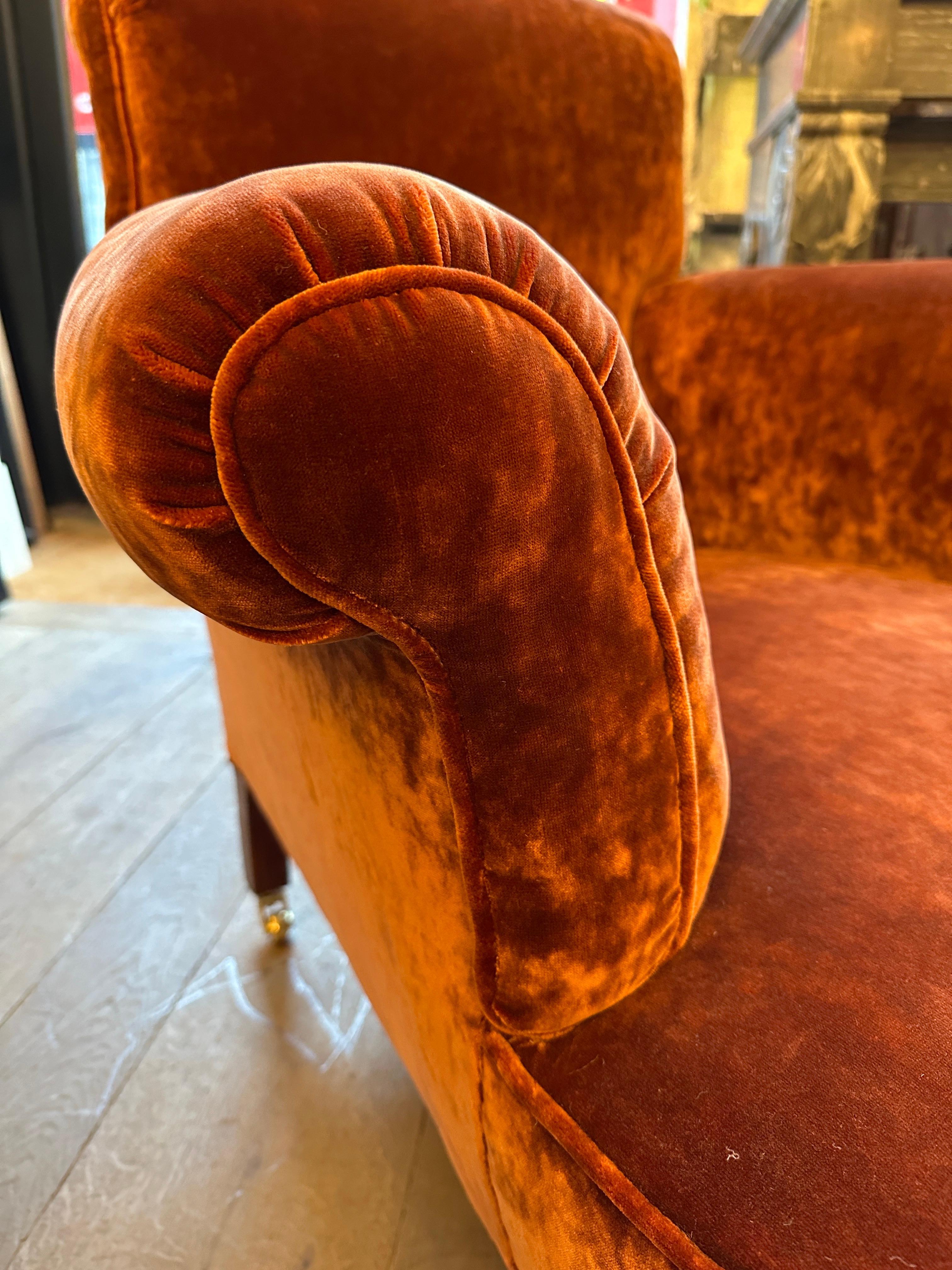 A large Victorian armchair or club chair newly re-upholstered in a crushed burnt umber coloured velvet. The roll back and arms with piped edges, new brass casters with studded legs. The crushed velvet giving a lived in finish, deep seated and