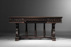 A richly carved Renaissance-style oak desk with a leather writing surface