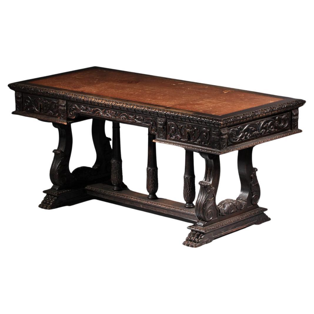 A richly carved Renaissance-style oak desk with a leather writing surface