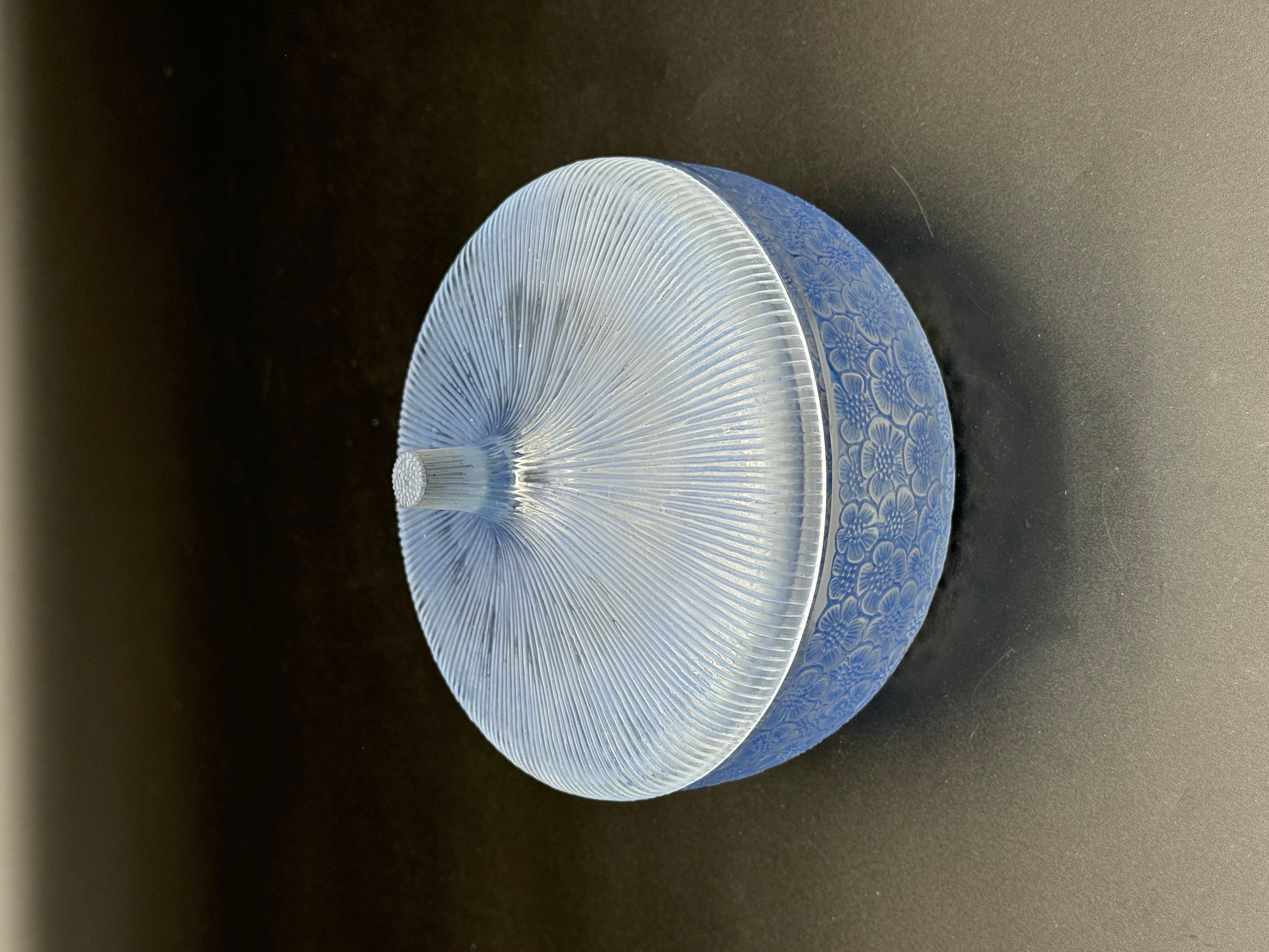 The Eglantines glass boxe is a strong Art Deco design of R.Lalique dating back to the 1926.

The boxe is in white glass and blue patina and has a blue patina .

The signature is molded in block letters .

The boxe is in perfect condition and