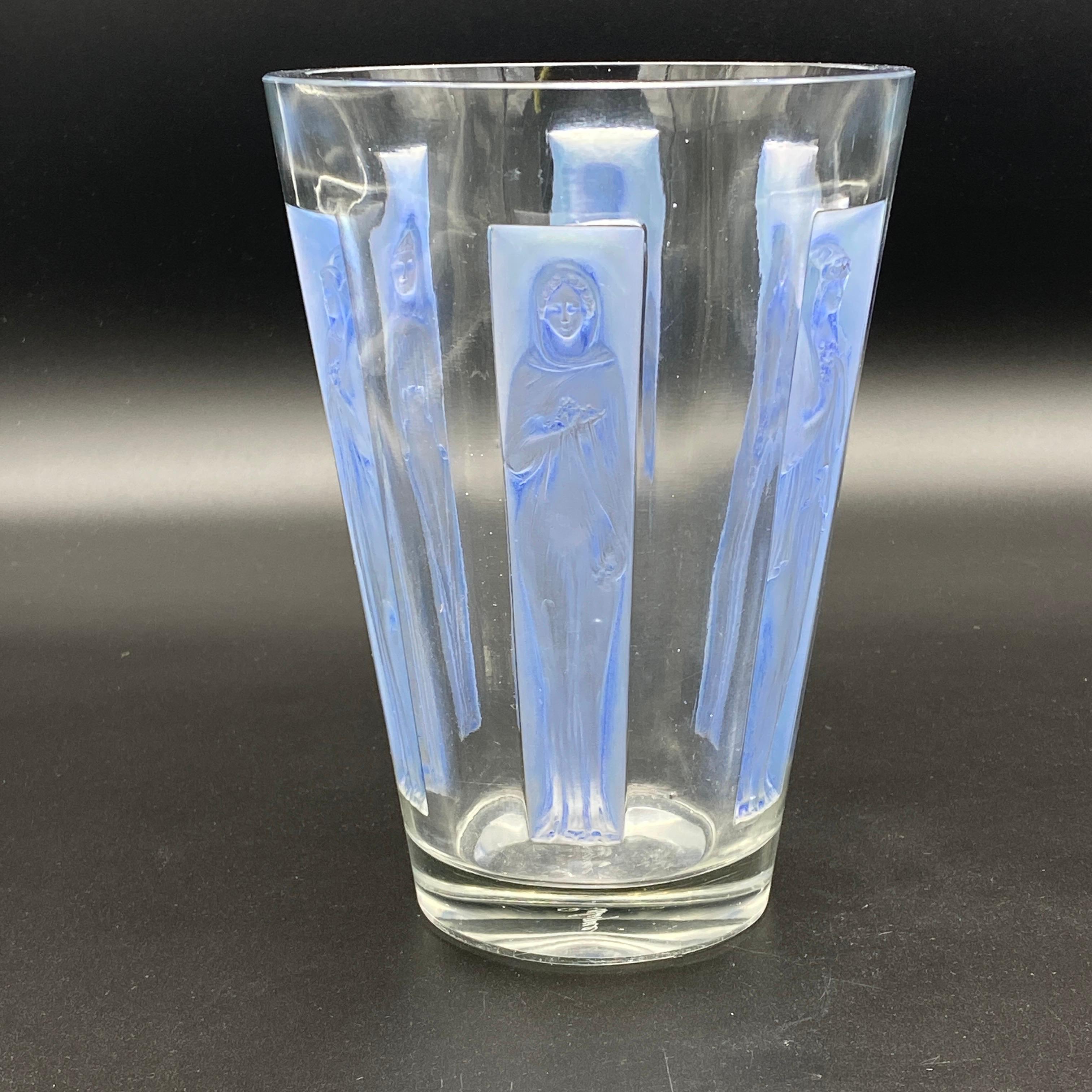 The Gobelet 6 Figurines vase was made by R.Lalique in 1920 in white glass.

This piece is an early example as the mold is very sharp as the molded signature on the side of a Figurines shows.

The glass is in excellent condition with a blue patina on