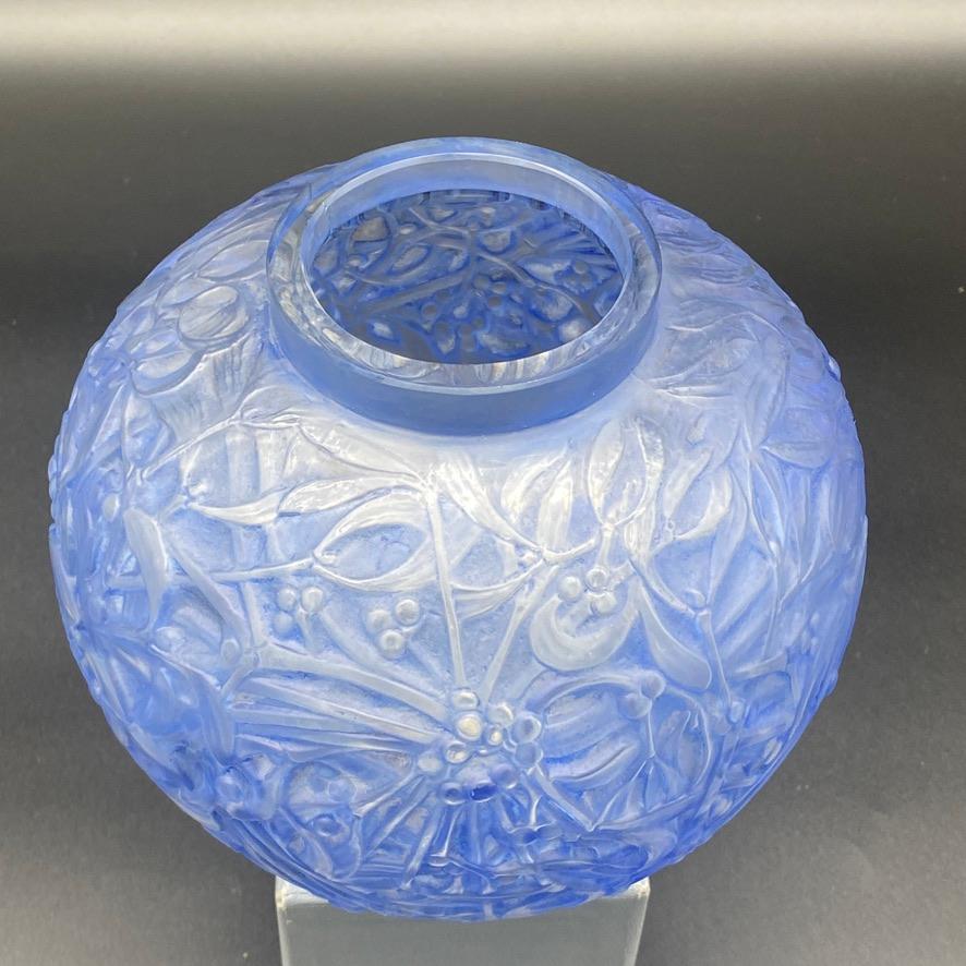 The Gui vase was made by R.Lalique in 1920 in white glass.

This example is in white and blue patinated glass and in excellent condition.

The vase has kept the retailer's sticker .

The signature is molded in block letters.