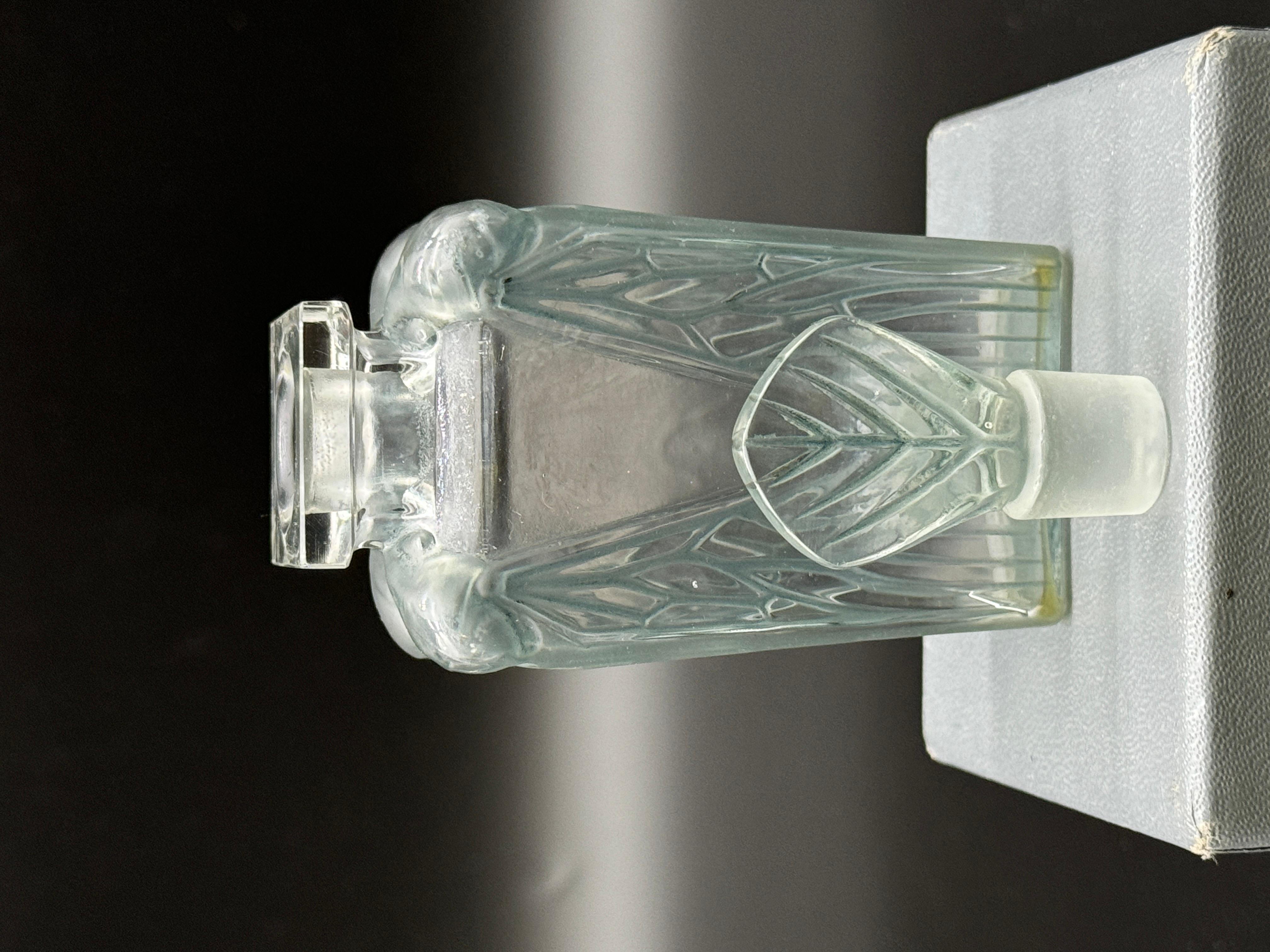 The Cigalia is one of R.Lalique ‘ s first creations for the Perfum Companys. in the early 1910.

It is strongly influenced by the Art Nouveau Style in white and green patinated glass .

It measures 13 cm high and is in excellent condition.

This