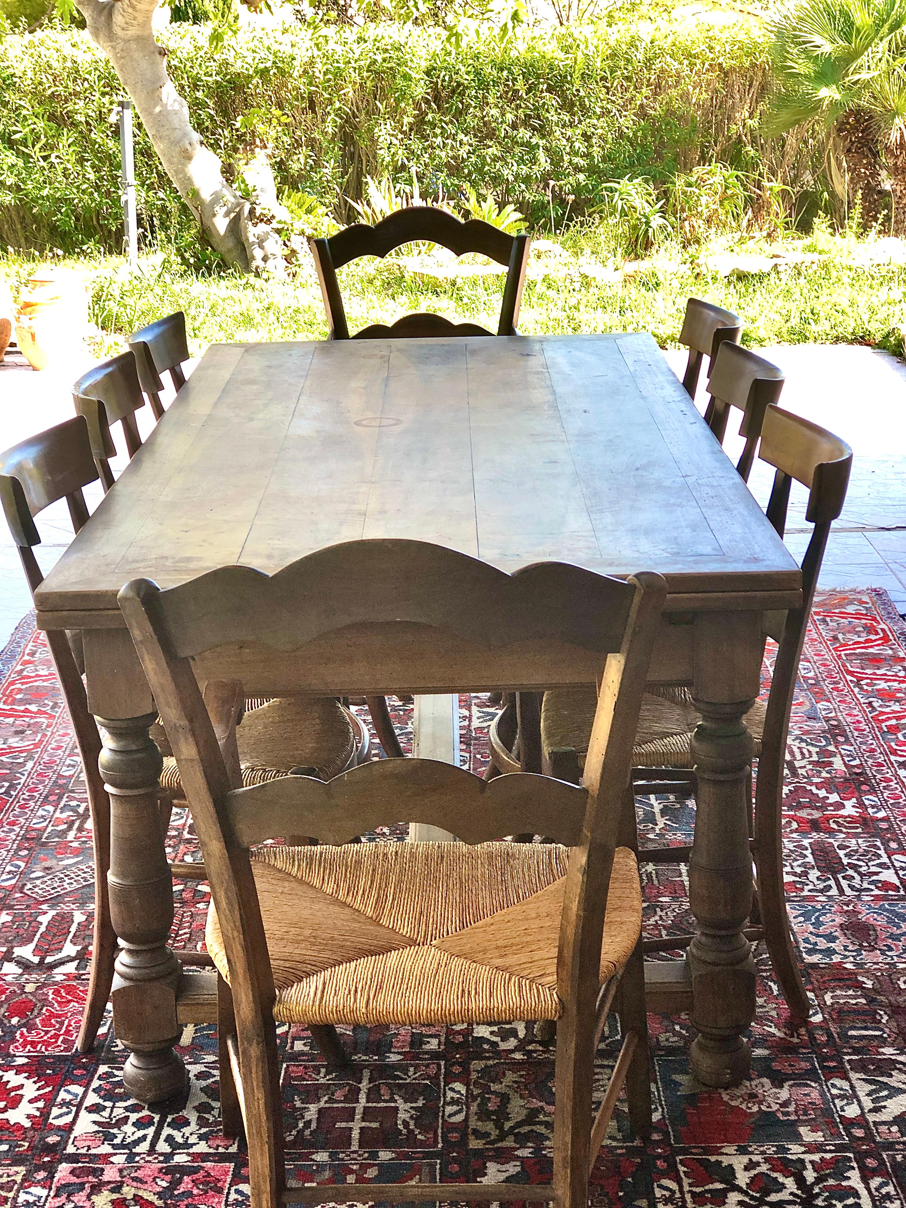 A robust 18th century French provincial farmhouse dining table, its warmly patinated rectangular top supported by four baluster-turned legs, joined by an 'entretoise' (H stretcher). Boasting two “allonges à l'italienne” (Italian-style extenders),