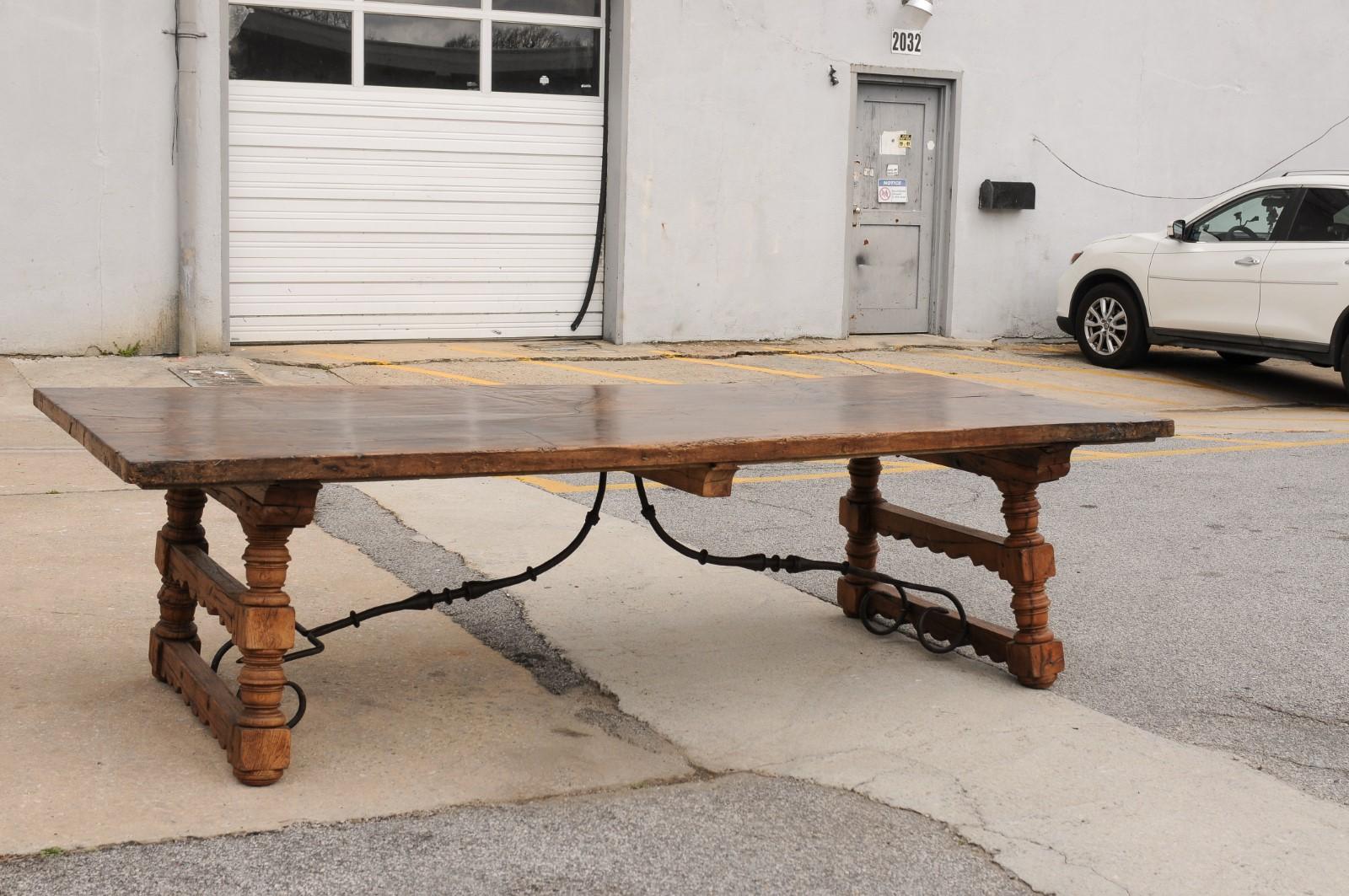An Italian antique large-sized wooden dining table with forged iron stretcher. This table from Italy was constructed in the early 20th century, but with older 19th century boards used for the top- which are nice and solid at 2.25
