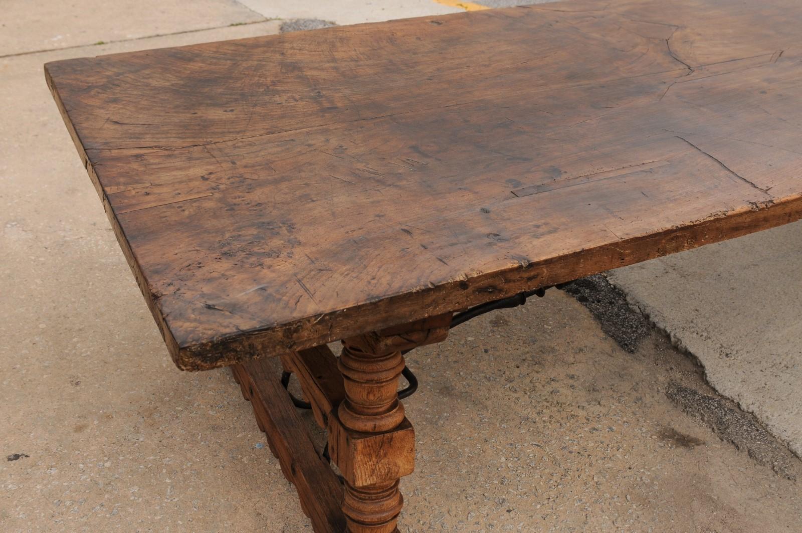 Una robusta mesa de comedor italiana de 3 metros con patas de caballete talladas y camilla de hierro siglo XIX en venta