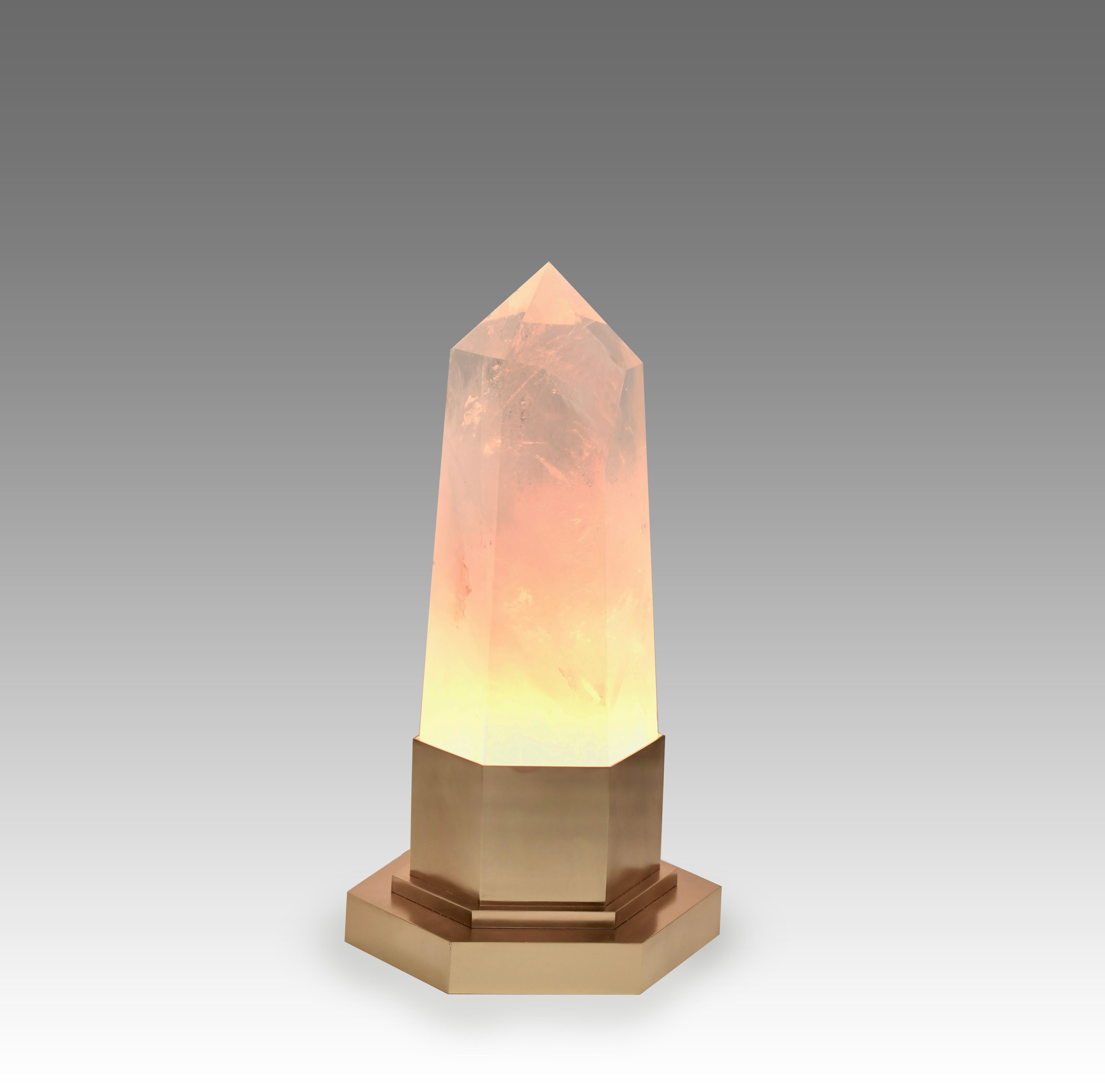 Une lampe obélisque en cristal de roche avec une base dorée mate. 
Deux prises installées. Fourniture de deux lumières chaudes led. 120w max.