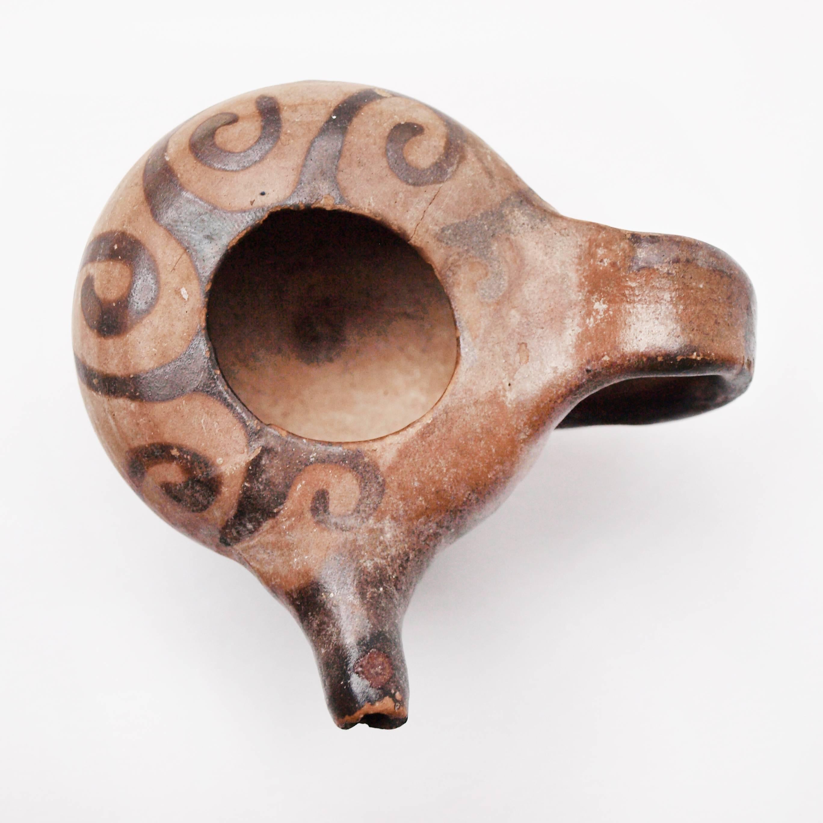 This wonderful Roman Apulian xenon-ware baby feeder is made from terracotta with a darker painted scrolling pattern surrounding the opening. 

