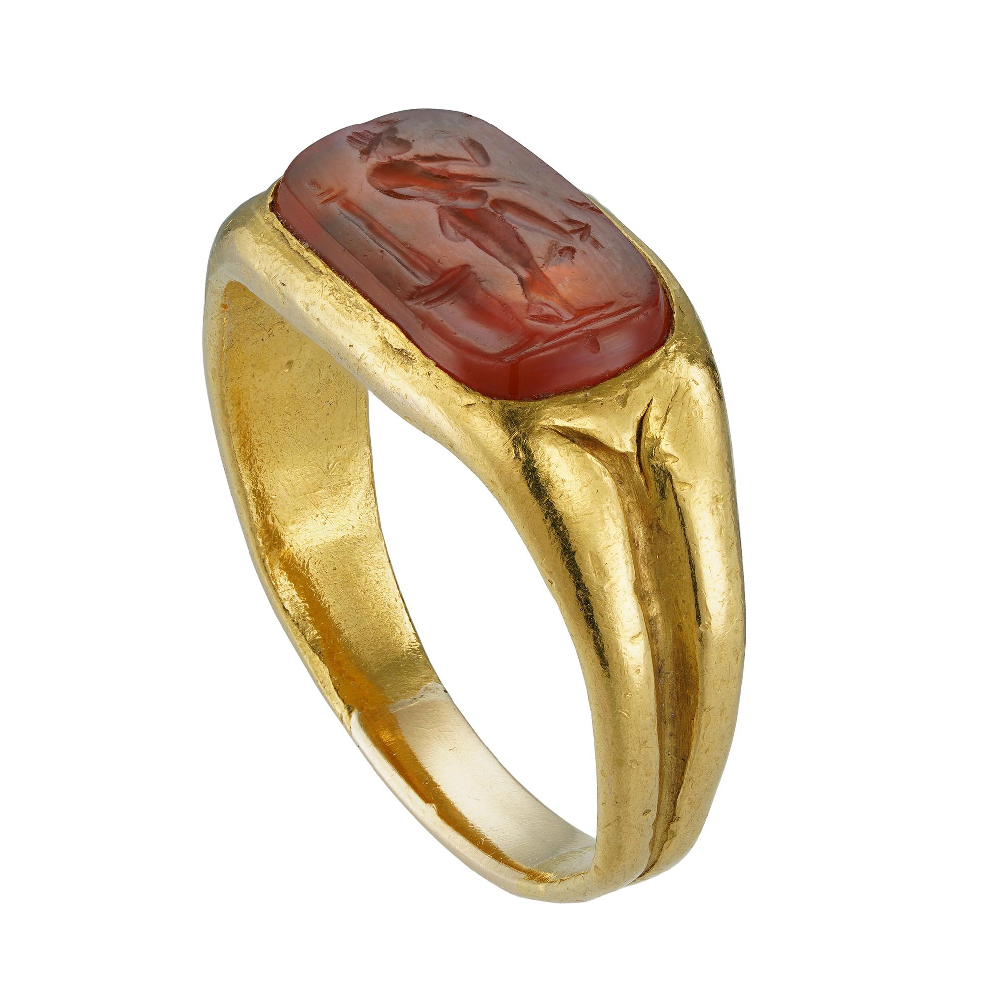 A Roman carnelian intaglio gold ring, the rectangular-cut carnelian intaglio measuring 1.3 x 0.7cm, depicting a victorious soldier, possibly carved in the 1st century, roman-set in a landscape positing to a yellow gold mount with closed back and