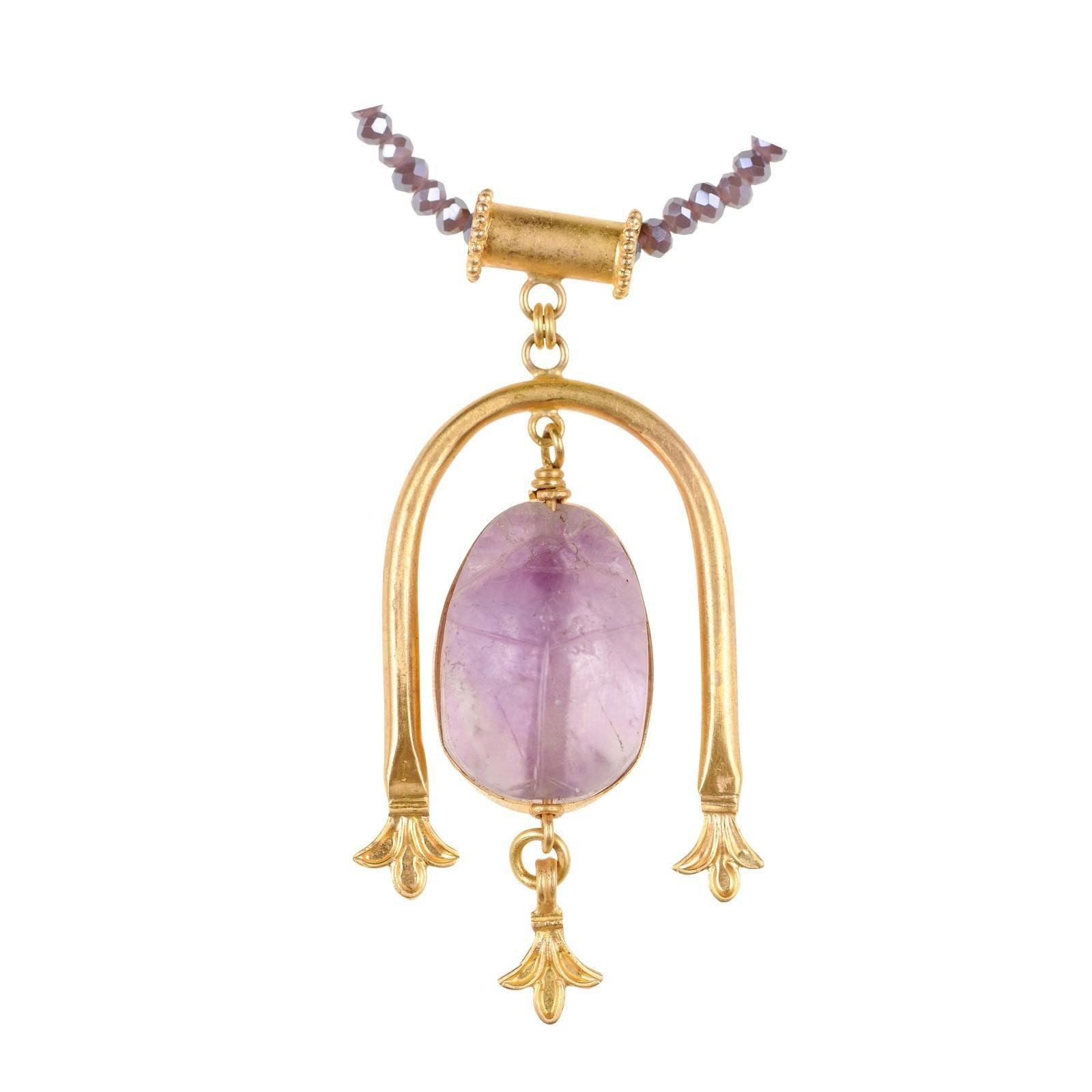 Scarabée d'Égypte romaine de couleur lavande (circa 100 BC-100 ADS) serti dans un pendentif décoratif en forme de goutte d'eau en or 21 carats et une attache. Ce magnifique scarabée d'améthyste violette a probablement orné une bague ou un autre