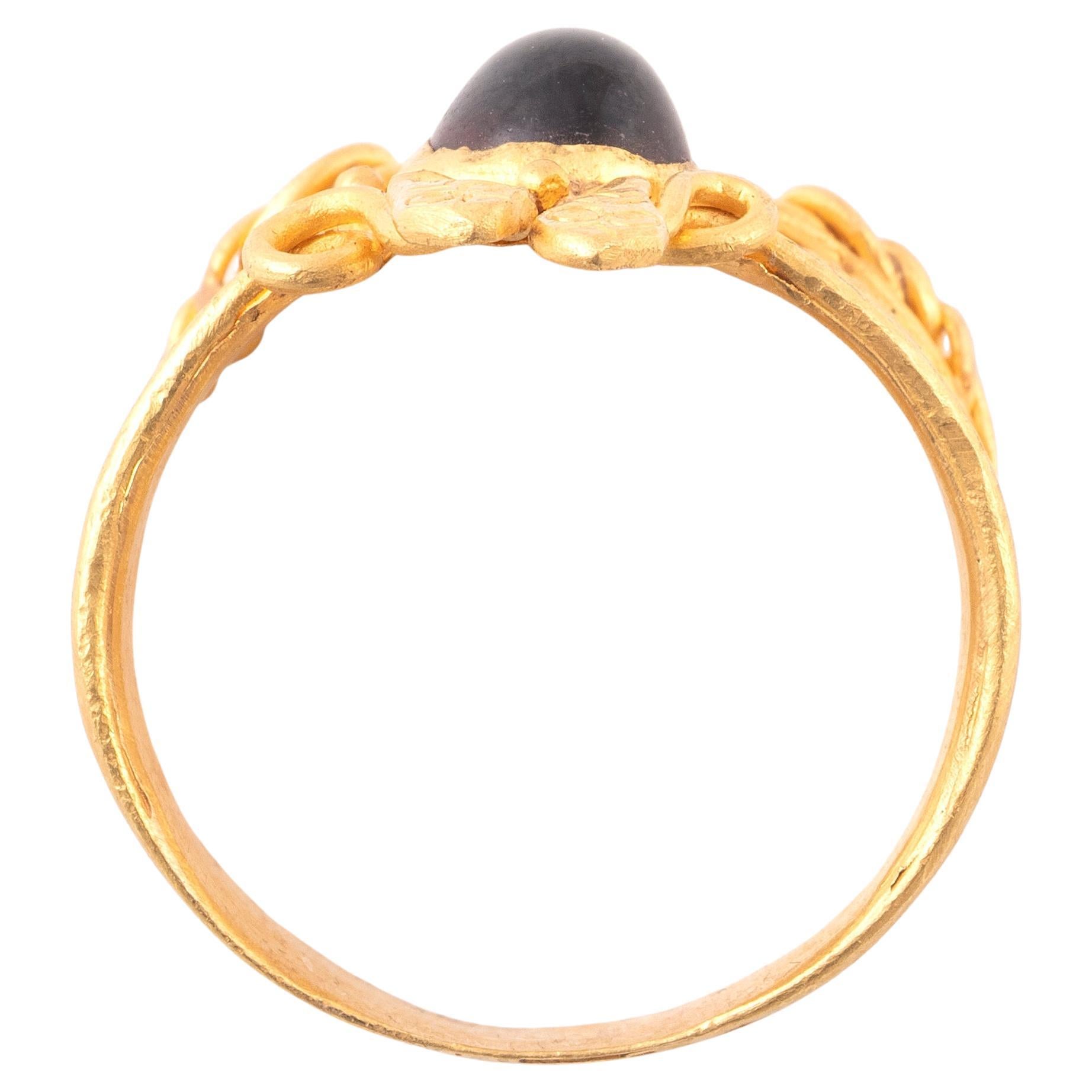 Ein feiner altrömischer Ring mit rundem Querschnitt und sich ausdehnenden Schultern, der aus einem einzigen Goldblech gehämmert wurde. Oben zwei Schlangen nach oben und in der Mitte ein Cabochon-Granat mit einem tiefroten Farbton. 

Ringgröße: