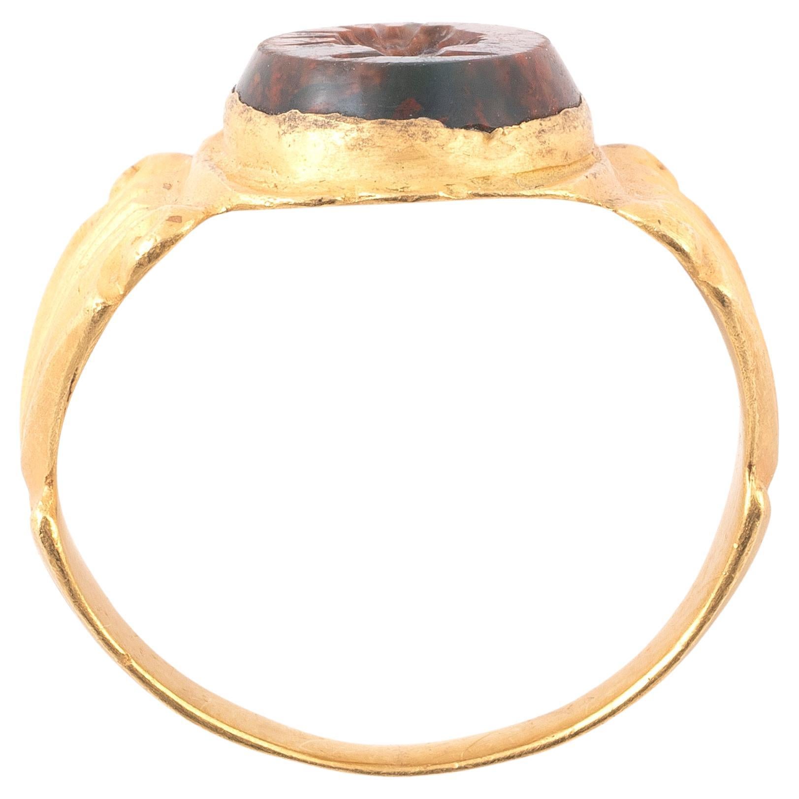 Un esempio estremamente raffinato di anello da dito romano massiccio, caratterizzato da un cerchio largo e angolare con volute profondamente intagliate sulle spalle, che creano un piacevole motivo di foglie d'alloro e incorniciano il castone.
II