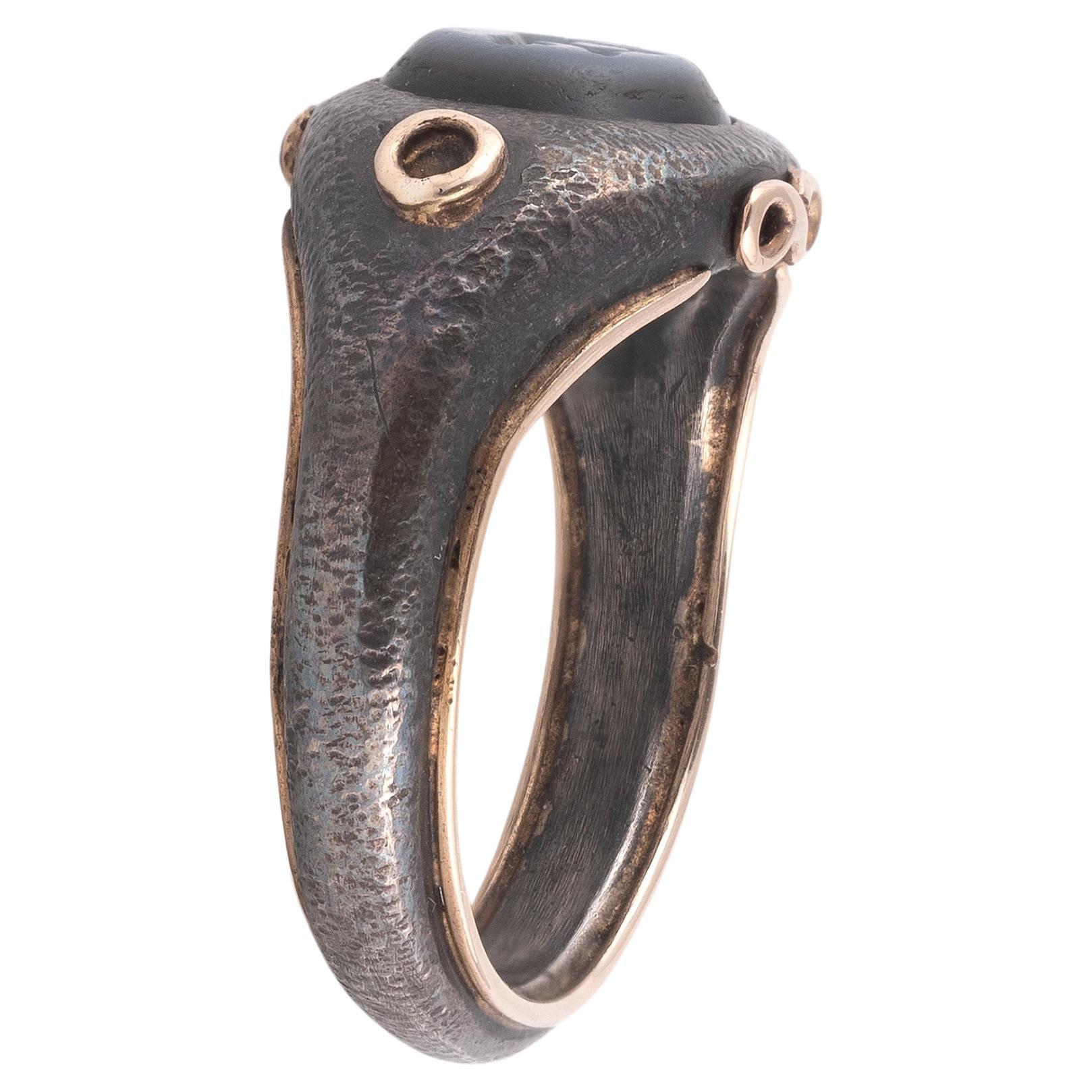 The oval stone engraved, depicting a panther, finger size 7 , the stone 7mm high, set in a modern silver and gold ring
Weight: 7.42gr.