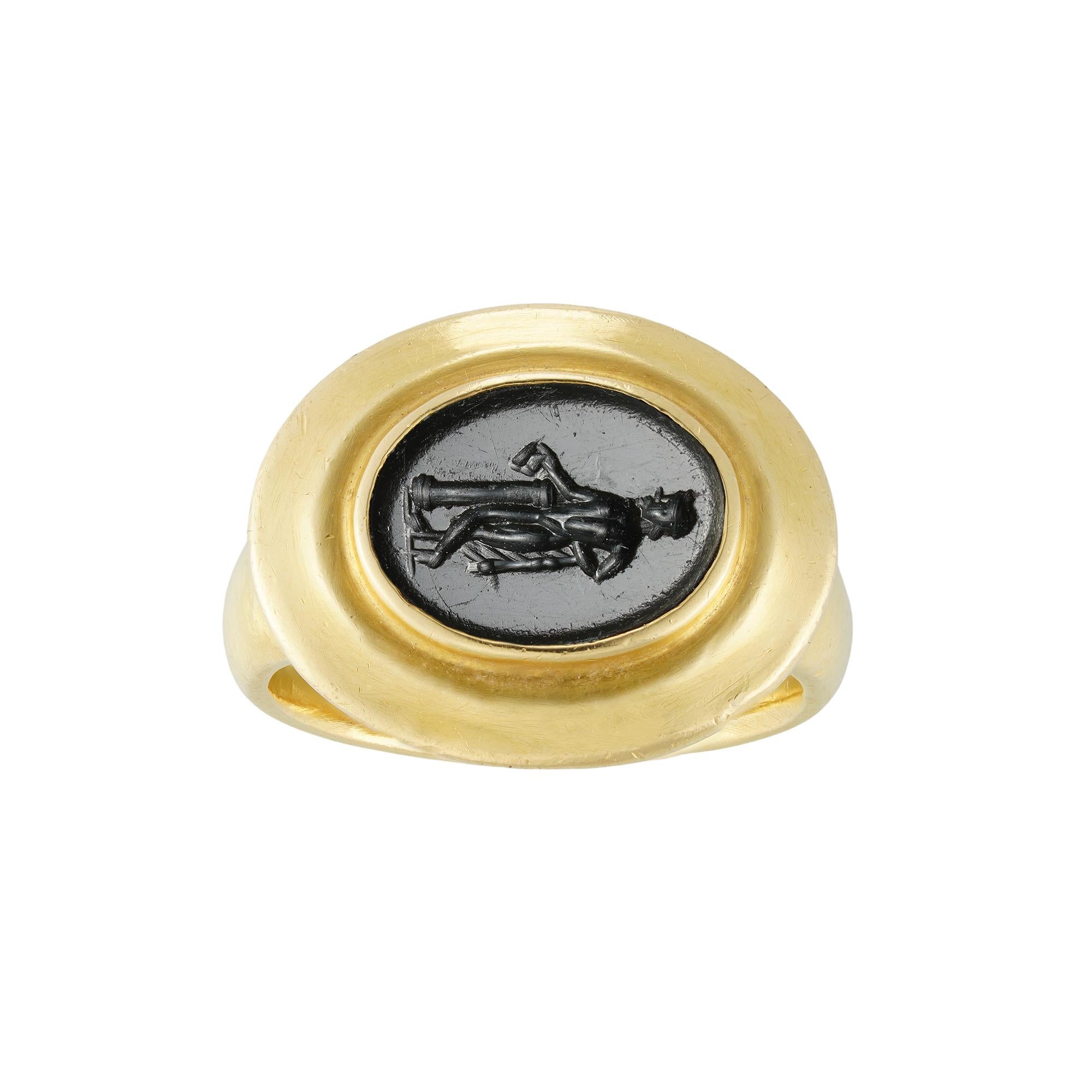 A Roman onyx intaglio and yellow gold ring, the oval- shaped onyx measuring approximately 11 x 8.5 mm, depicting Dionysus leaning on a column and holding a kantharos, carved in 1st-2nd century AD, rub-over set in later yellow gold mount, testing as