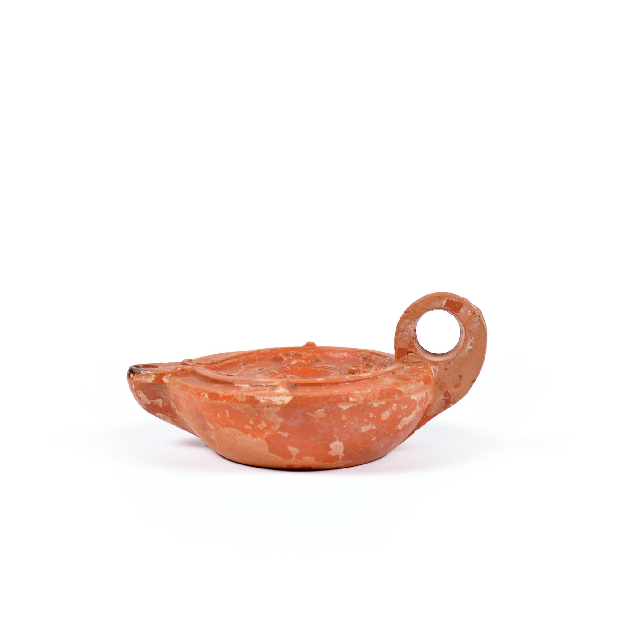 A Roman terracotta red slip ware oil lamp with theatre masks In Good Condition For Sale In UTRECHT, UT