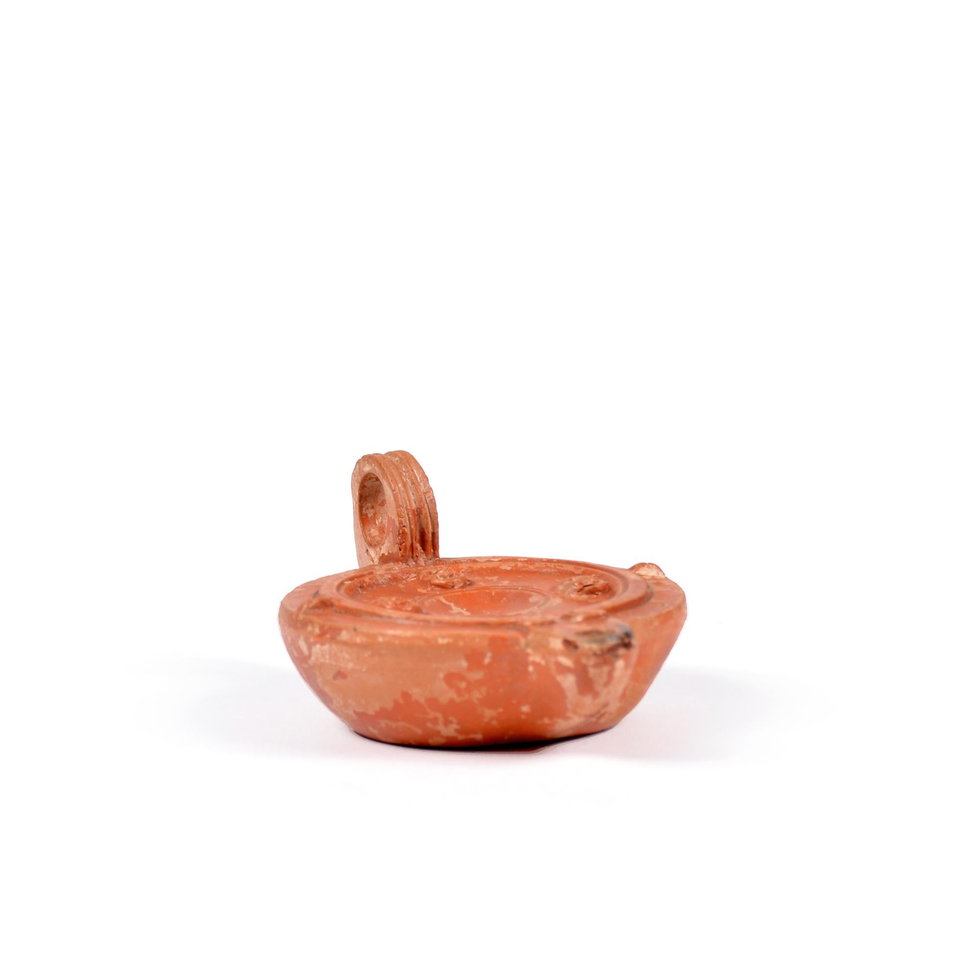 Terracotta A Roman terracotta red slip ware oil lamp with theatre masks For Sale