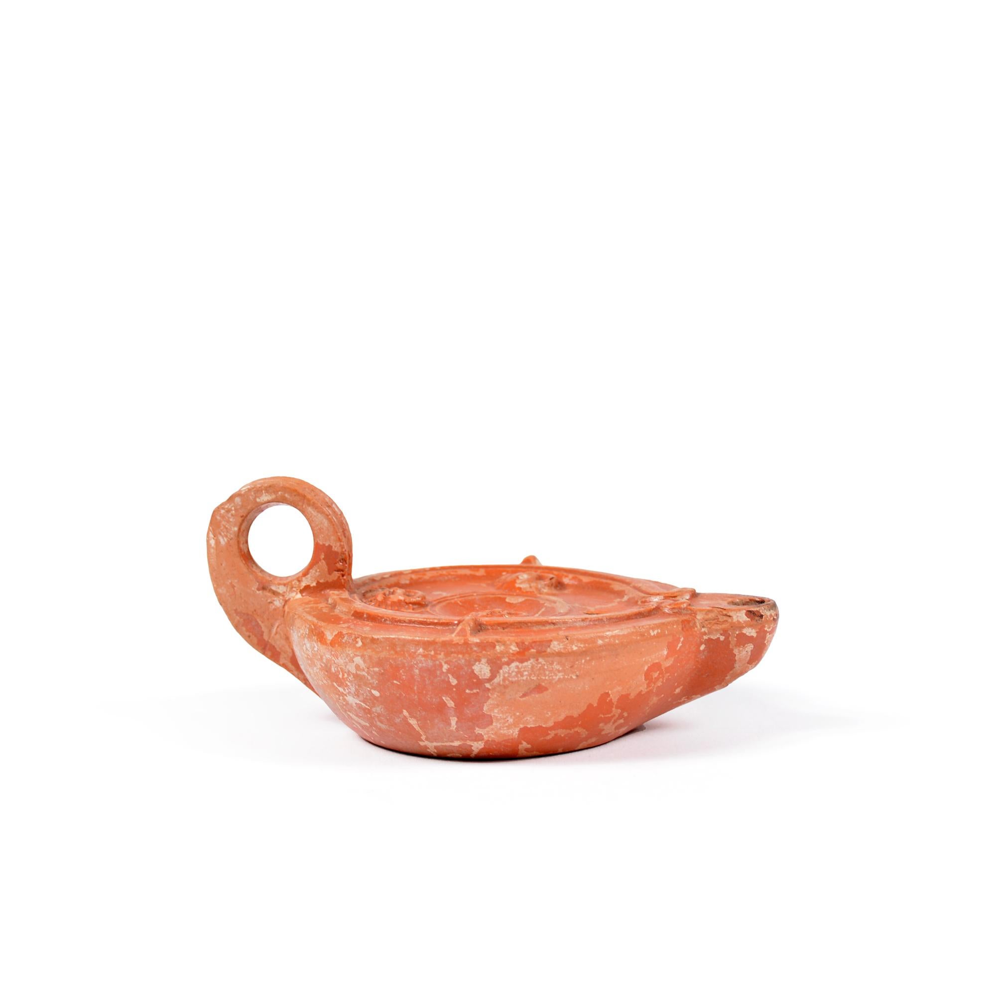 A Roman terracotta red slip ware oil lamp with theatre masks For Sale 1
