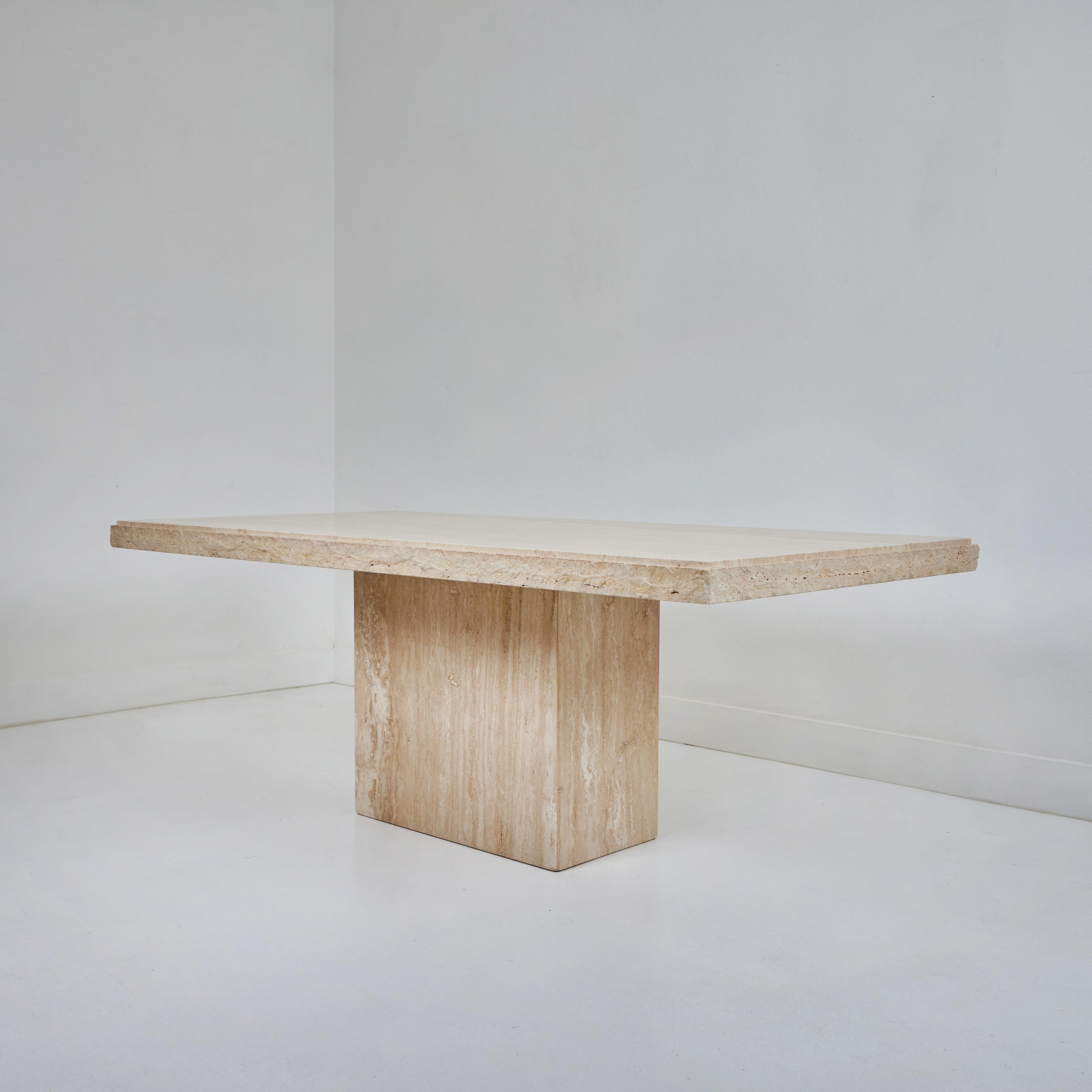 This quarry edge travertine table has a minimalist quality to it given the simplicity of the material. The exposed table top and the base are smooth. The table top has a quarry edge, beautifully blending the two textures. The table base measures