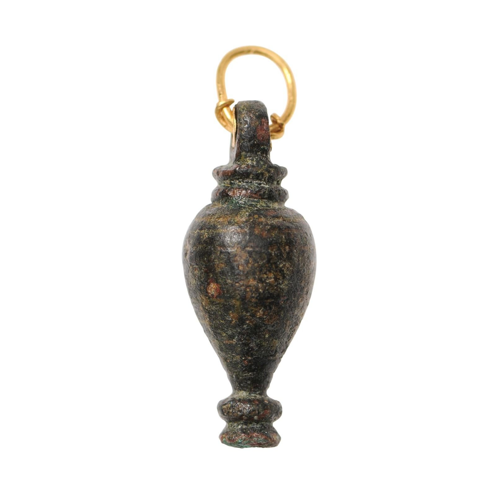 Una forma di fiore tornito o un vaso elegante trasformato in un ciondolo in oro 22 carati. Questa forma di vaso romano presenta una patina meravigliosa che dimostra l'età del ciondolo. Questo esemplare, risalente al I e III secolo d.C., è stato
