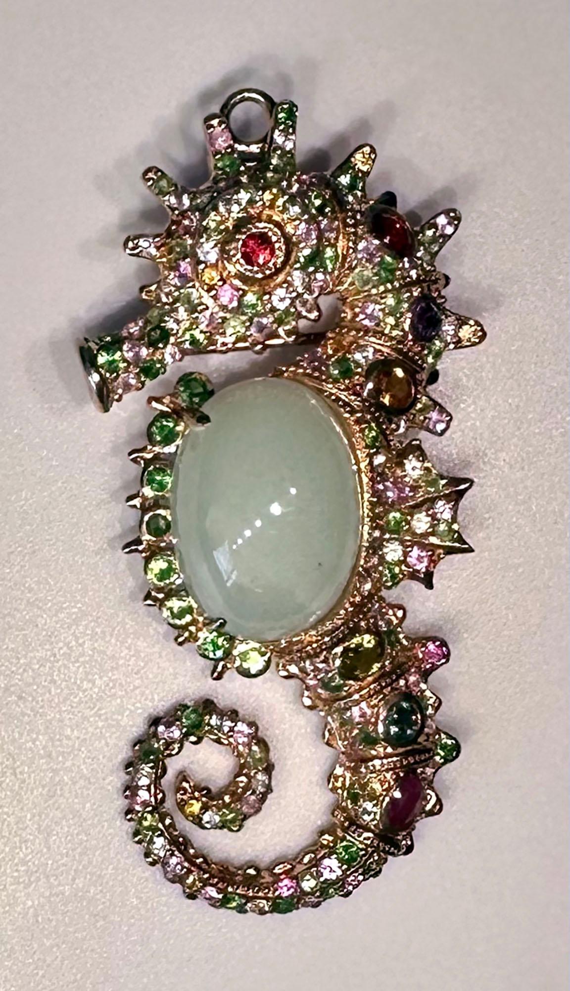 A Rose Gold Plated, Silver Seahorse Brooch/Pendant set with a milky Aquamarine Cabochon, Tsavorite, Sapphire, & Tourmaline. This pave encrusted seahorse has a of,d down loop dial so it can be worn as a pendant as well as a brooch. This is a