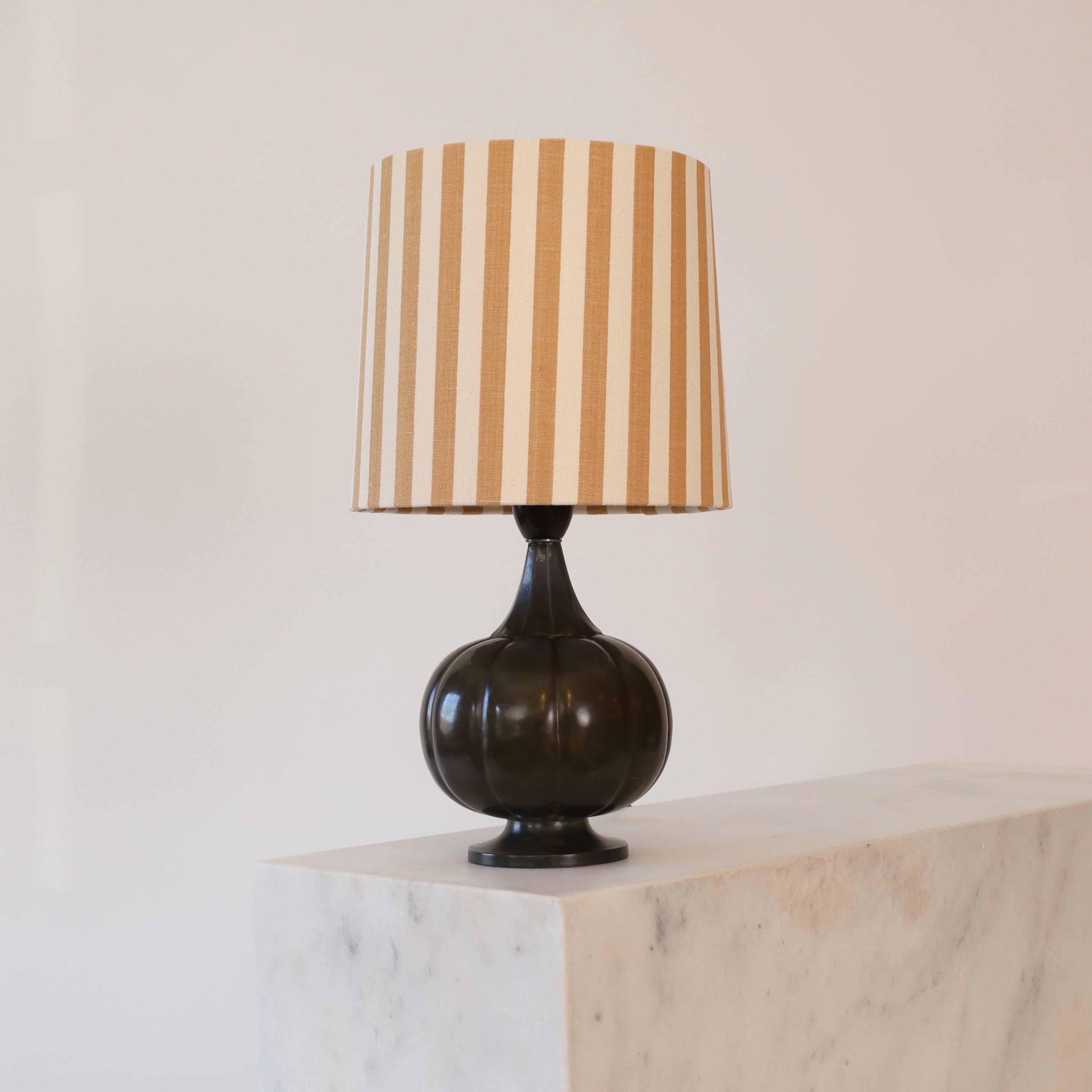 A pumpkin-shaped table lamp designed by Just Andersen in the late 1920s. A fine lamp for a beautiful home.

* Pumpkin-shaped metal table lamp on foot with a fabric shade with cognac-coloured stripes.
* Model: 1273 (stamped ‘Just 1273’)
* Year: