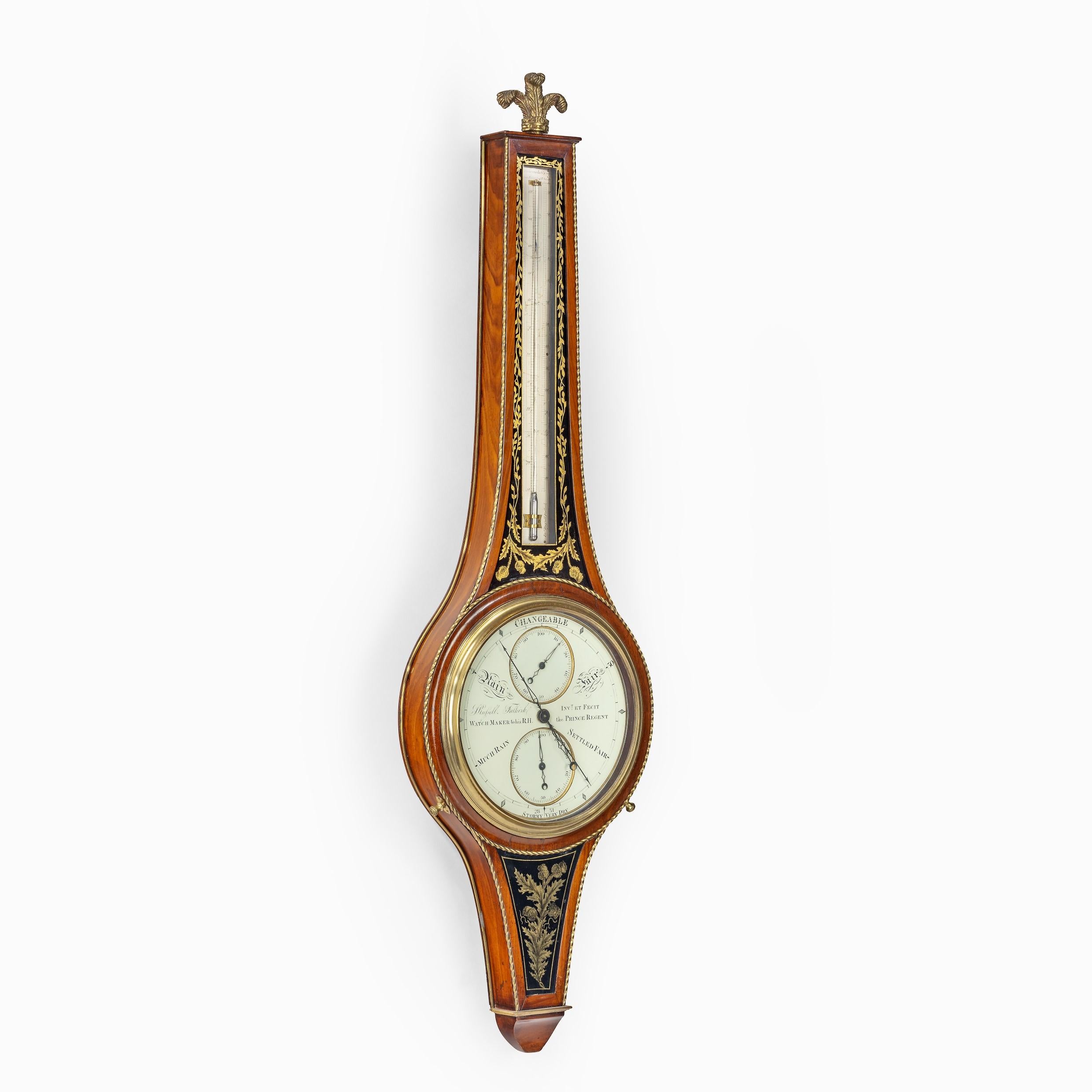 This superbly crafted wheel barometer and thermometer has a mahogany case surrounded by twisted brass stringing and central panels of foliate tendrils above Russell’s signature thistle motif in black and gilt verre églomisé. It is surmounted by a