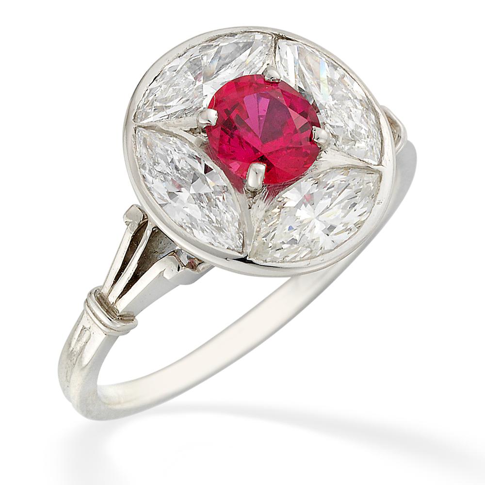 A Ruby And Diamond Ring the oval panel centred with an oval ruby weighing 0.74cts surrounded by four marquise diamonds weighing a total of 1.48cts, all set in a platinum mount with fluted shoulders and reeded shank, hallmarked for platinum, London