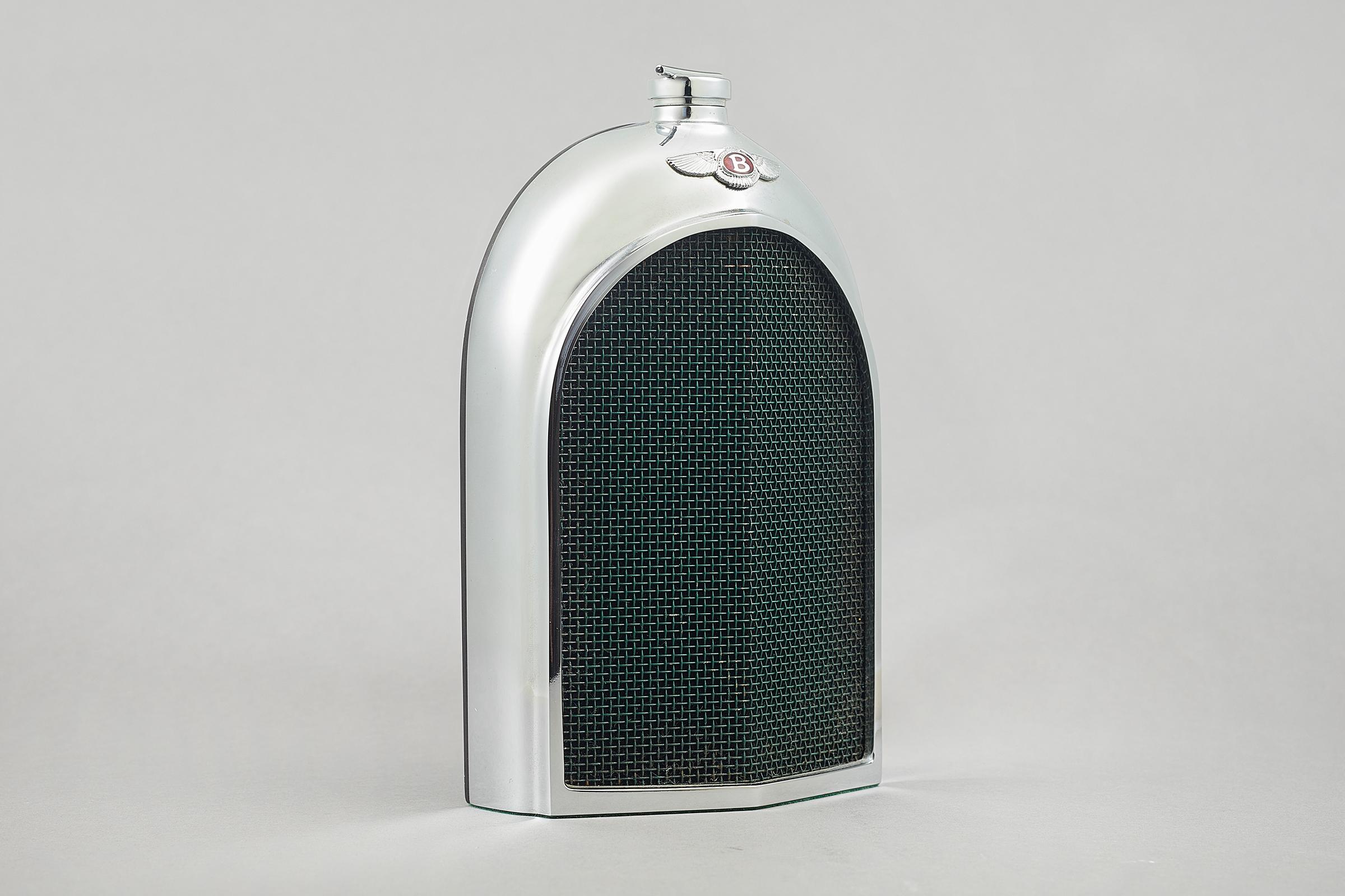 A midcentury Ruddspeed automobile decanter, circa 1960, in the shape of a Bentley radiator grille. Chromed metal with an enamelled green mesh grille and winged badge, and screw top. Designed and manufactured by Ken Rudd and Ruddspeed Ltd. of