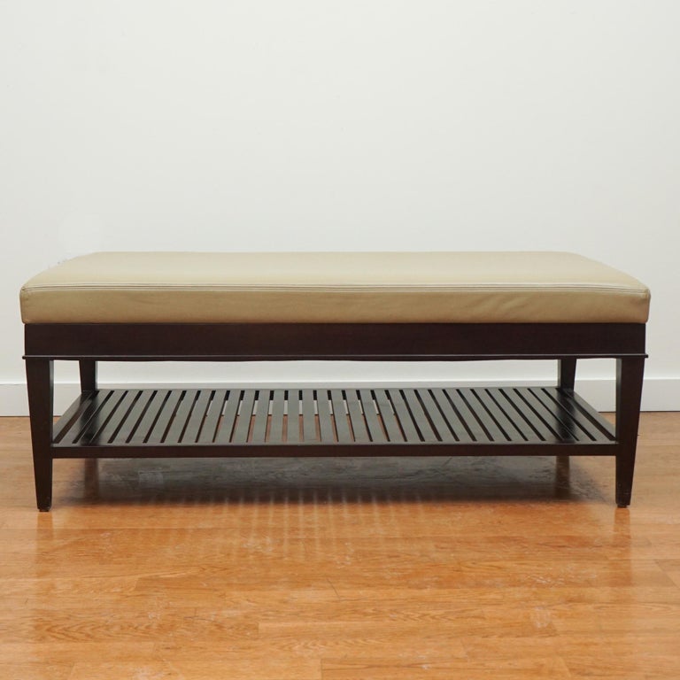 This leather bench/ottoman is from A. Rudin.  Finished in a dark wood tone, the scale and leather top makes it appropriate for use as an ottoman, bench or coffee table.  The slatted bottom shelf offers additional storage.   Made in the United