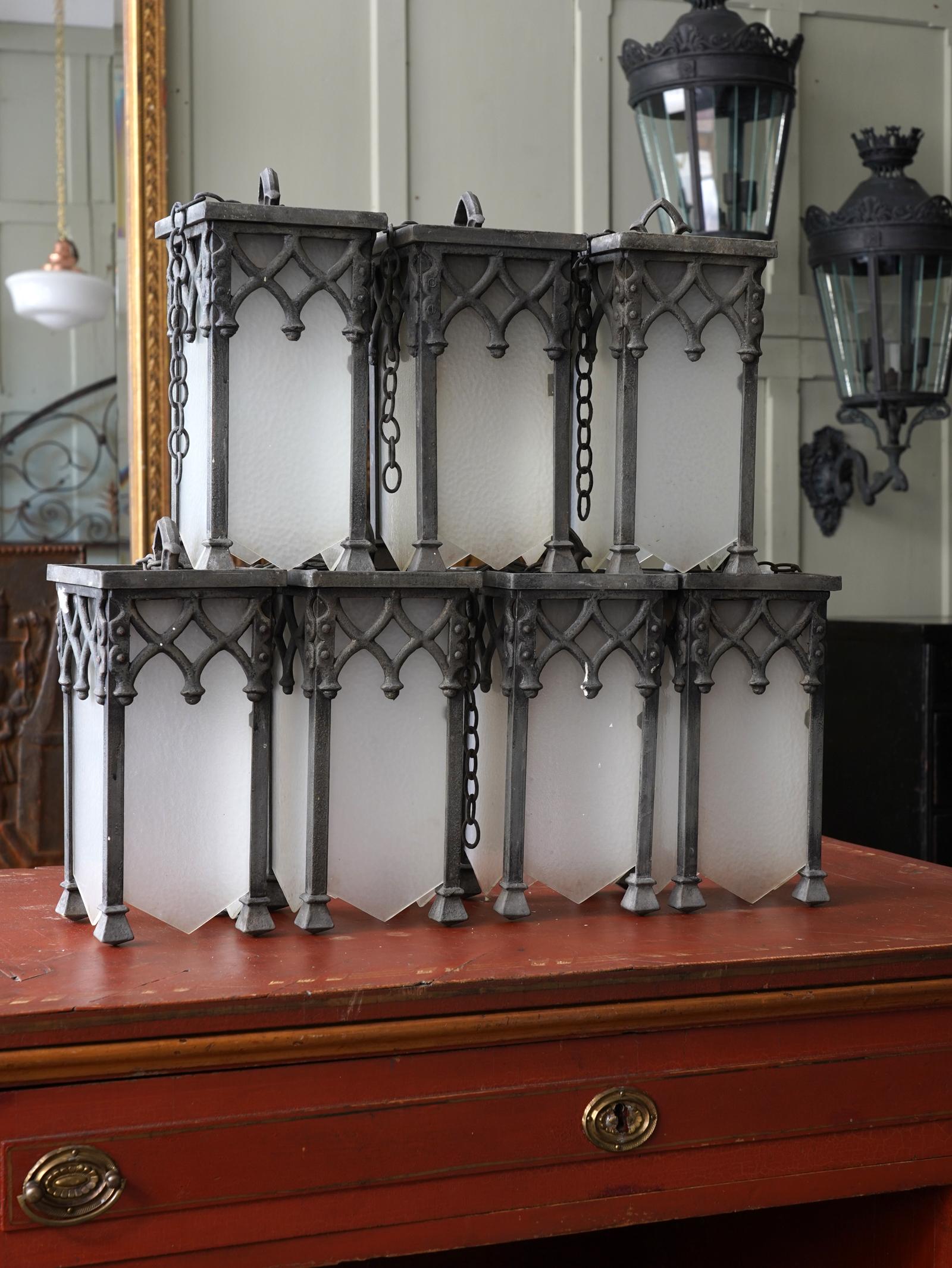 A run of early 20th century glazed lanterns in the Gothic manner.

Steel, wrought iron and cast alloy, remnants of the original painted surface, original acid etch glazing to all, the brackets are later and the lanterns can be hung by suspension