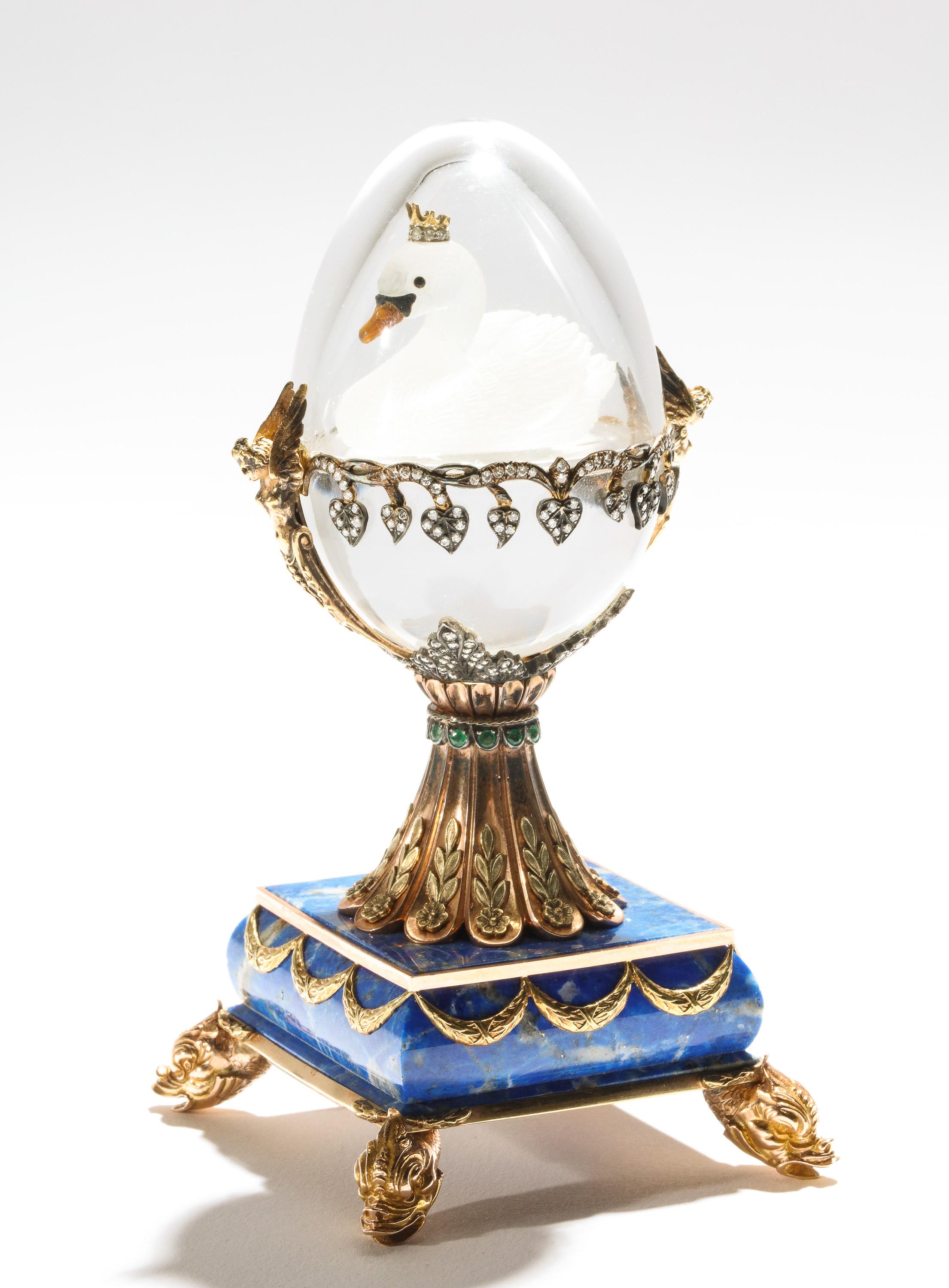A beautiful Russian 14- karat gold, diamonds, emeralds, lapis lazuli and glass egg with swan, by S. Rudle, 20th century.

Two color, 14-karat gold mounts, the egg in the Faberge style with a floating frosted glass swan, mounted with diamonds,