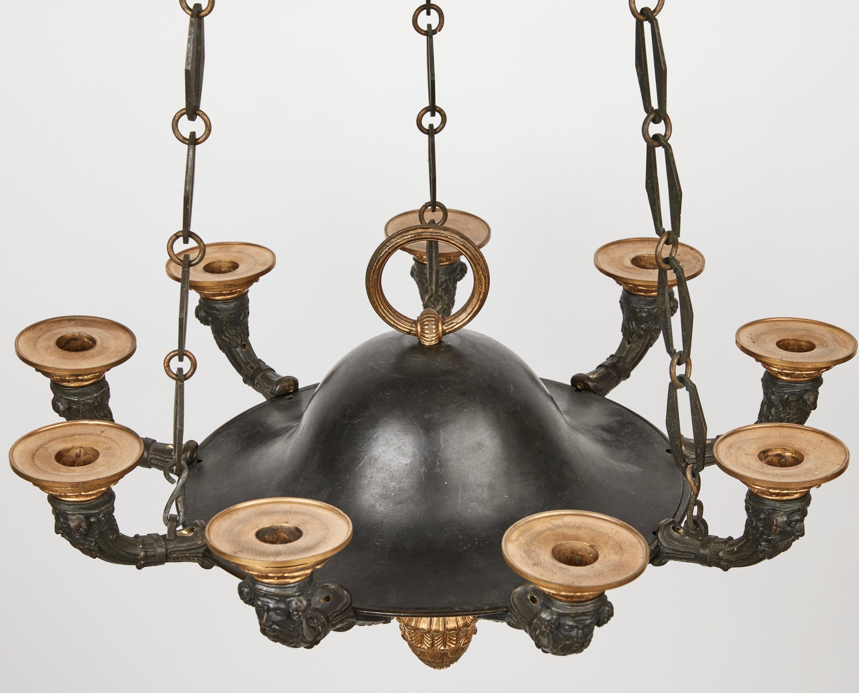 A nicely designed and large chandelier made for 9 candles. The cup/bowl is made out of patinated copper and the arms etc are gilt and black patinated bronze. The casting of te arms are of very good quality.