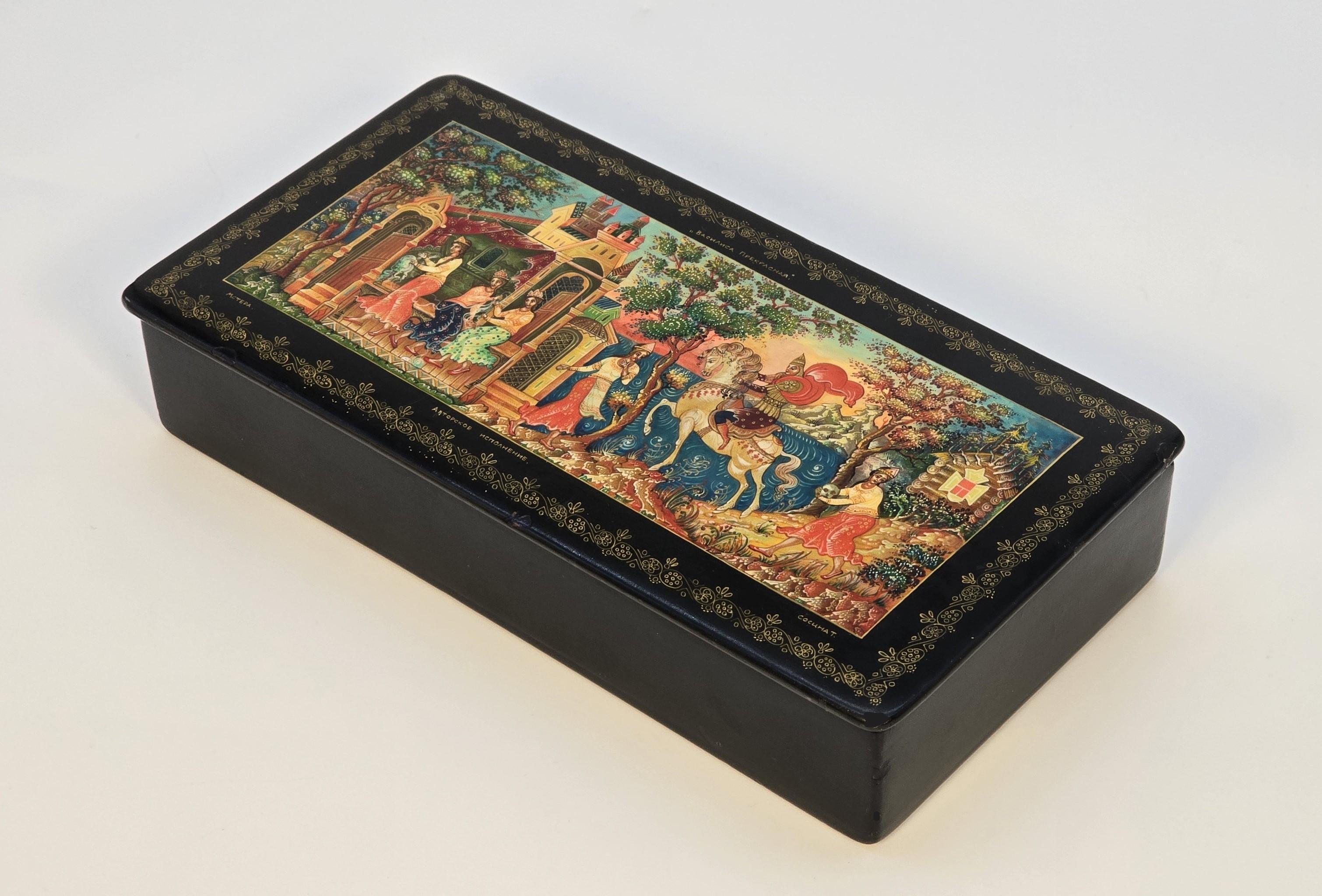 This top quality Russian black lacquered papier mâché box has an extremely fine hand painted central panel to its lid with a medieval scene set amongst a landscape with a castle and ornate buildings alongside a lake with mountains in the distance