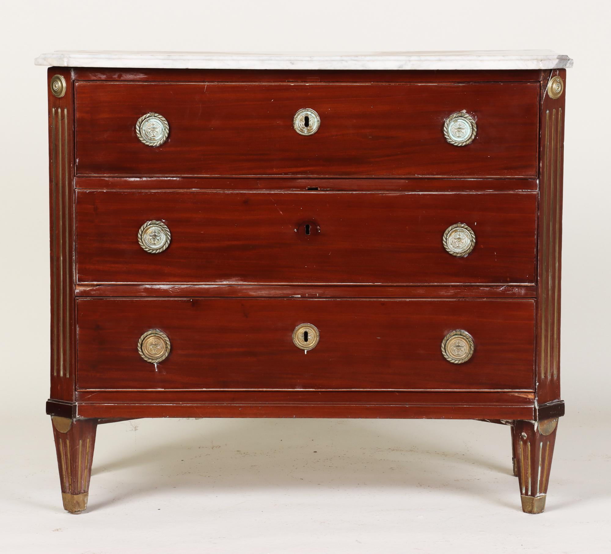 A Russian neoclassical brass mounted mahogany commode, early nineteenth century. Featuring a marble top with outset square corners above a case fitted with three drawers and ending in tapering square feet.