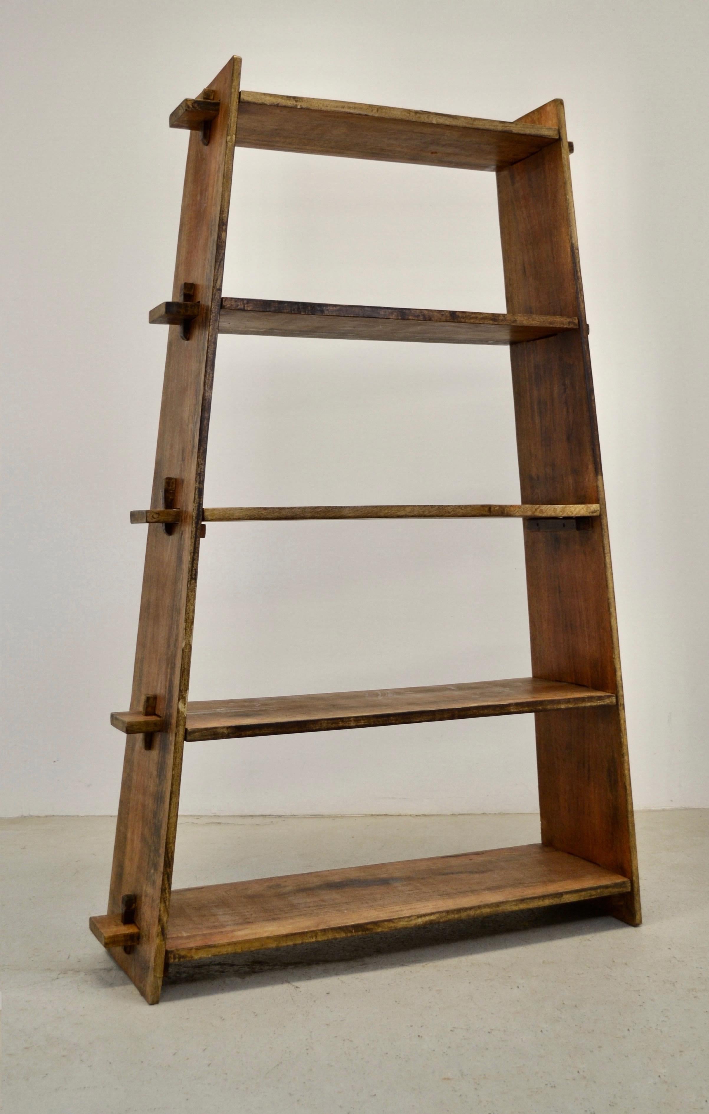 A rustic alpine shelf, representative of 20th-century French folk art, features two sturdy uprights and five solid wooden shelves intricately joined together with wooden pegs. The ingenious design allows for effortless disassembly, making