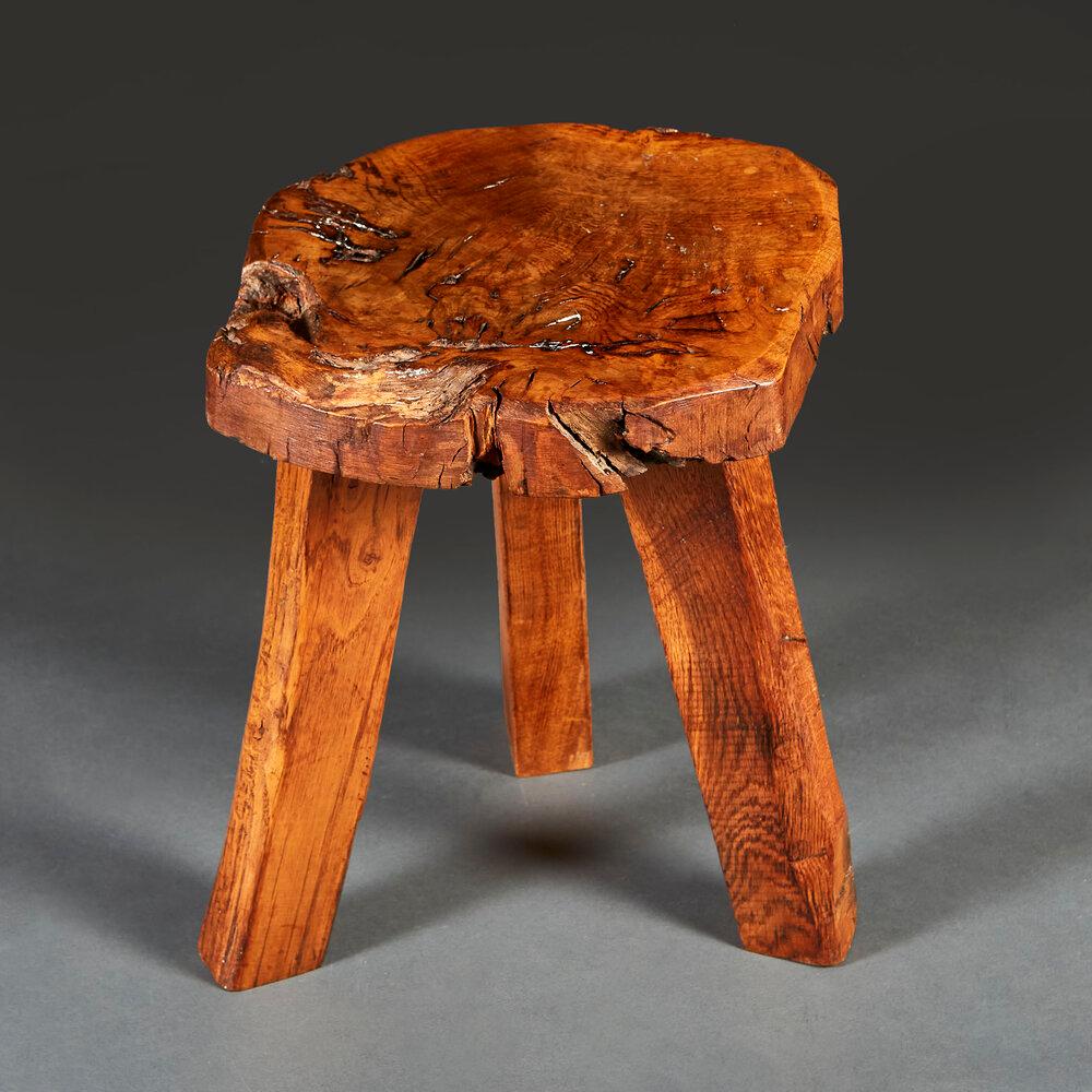 An early twentieth century rustic elm wood stool with burr top, all supported on a tripod base.