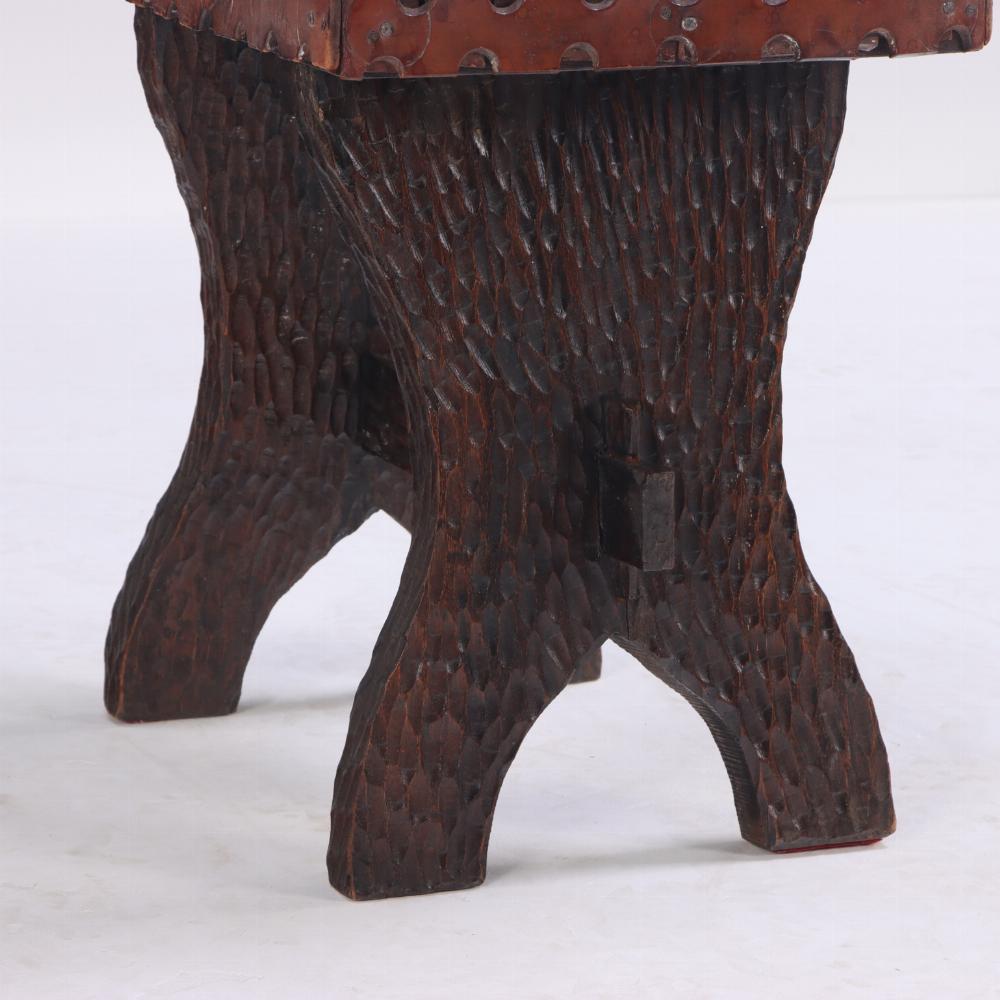 The seat constructed of strap work leather in a basket weave pattern, atop the Brutalist style carved stretcher base.