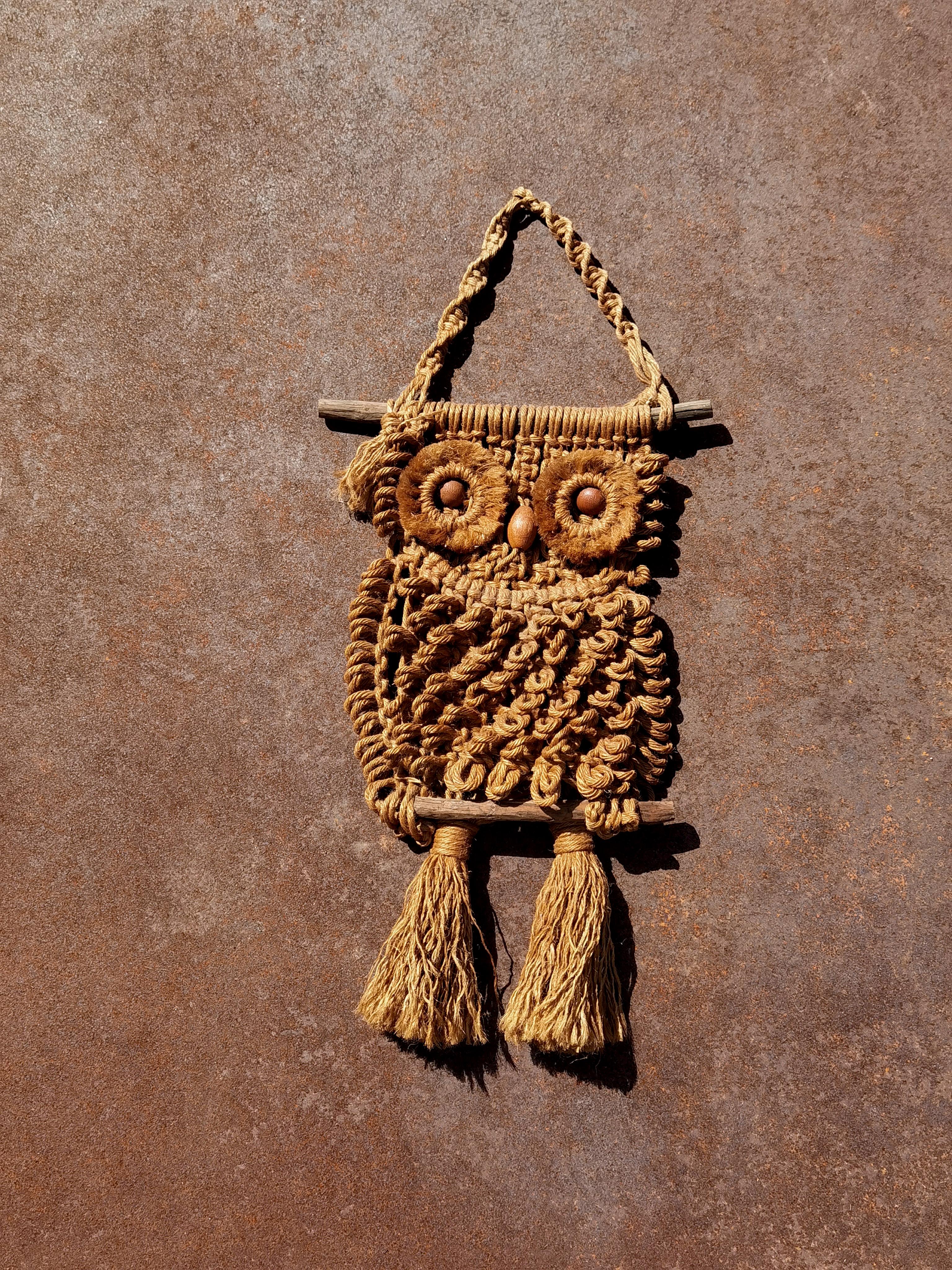 One (of a pair) sculpture or wall hanging representing a stylized owl, Handcrafted, Brutalist, Tribal, Modern Rustic, Hippie, Seventies, composed of braided rope(s) of varying thickness and quality(s) mounted on a suspended wooden structure/branch,