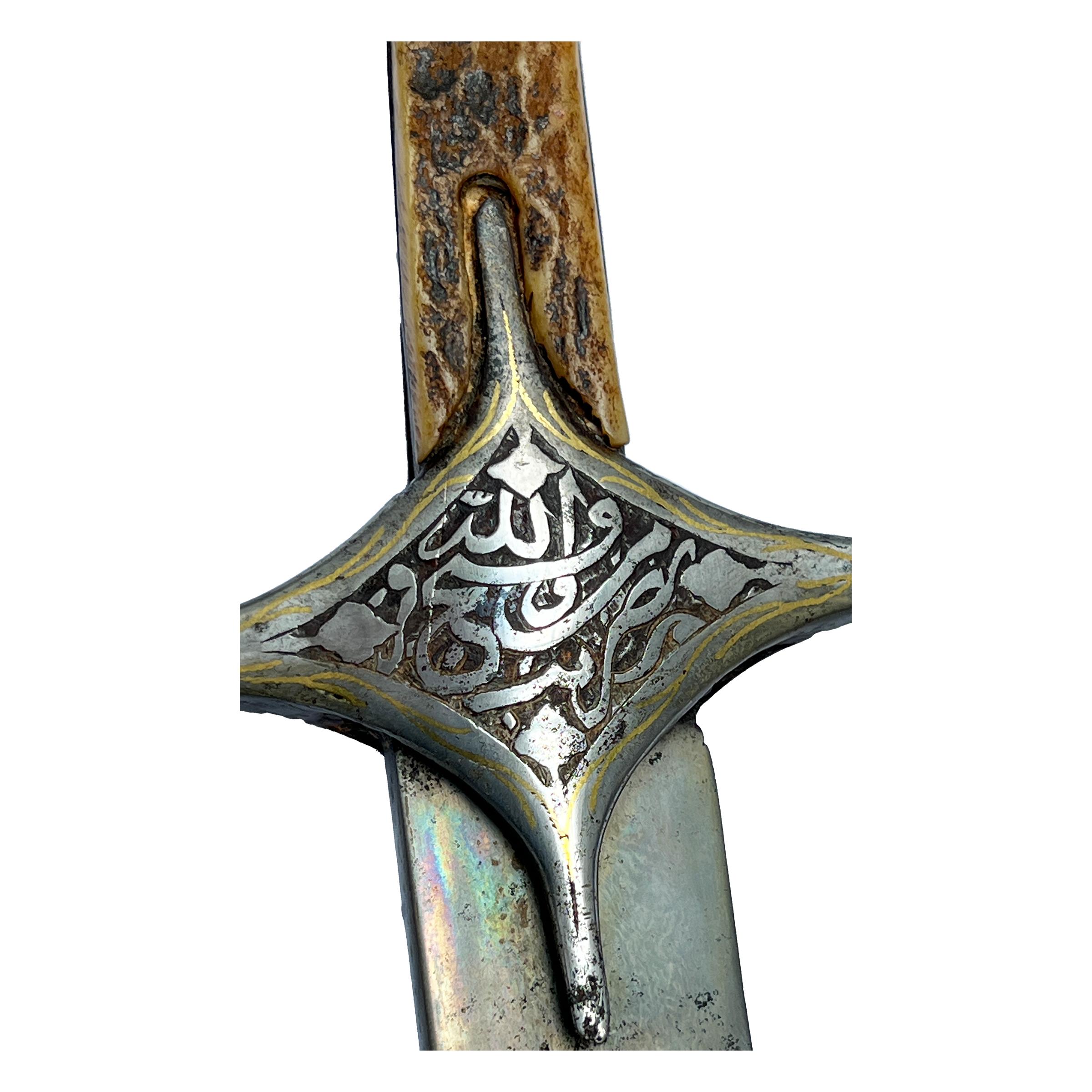 A Fine single-edged watered-steel blade of curved form with engraved inscription-filled cartouche, inscription-filled cartouche to the watered steel crossguard to each side and horn grip. 

Inscriptions: Bism Allah Alrahman Alrahem, Nasr Mn Allah