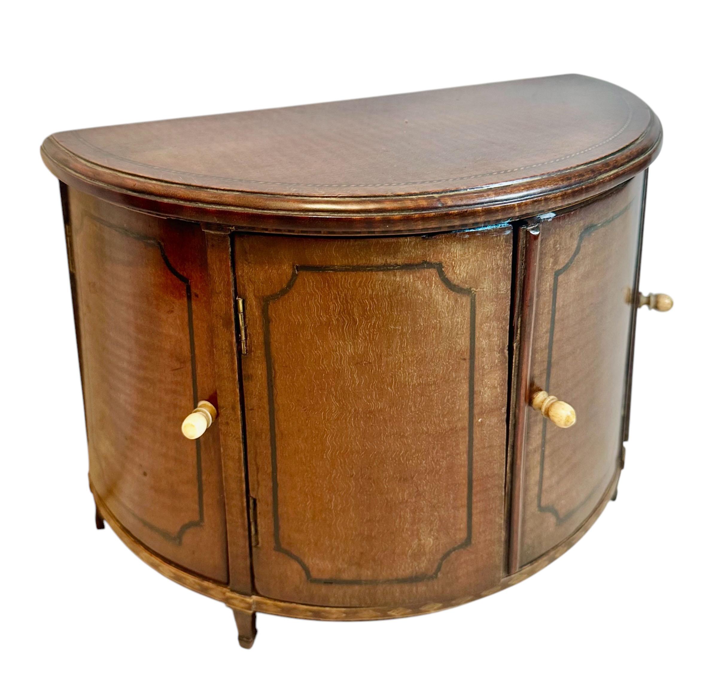 Ésta es una muestra de vendedor de un baúl inglés Demilune. Tiene cuatro puertas con un tirador de barra de marfil. Está toda incrustada alrededor de la parte superior e inferior. Se asienta sobre cuatro patas. Circa 1800s.