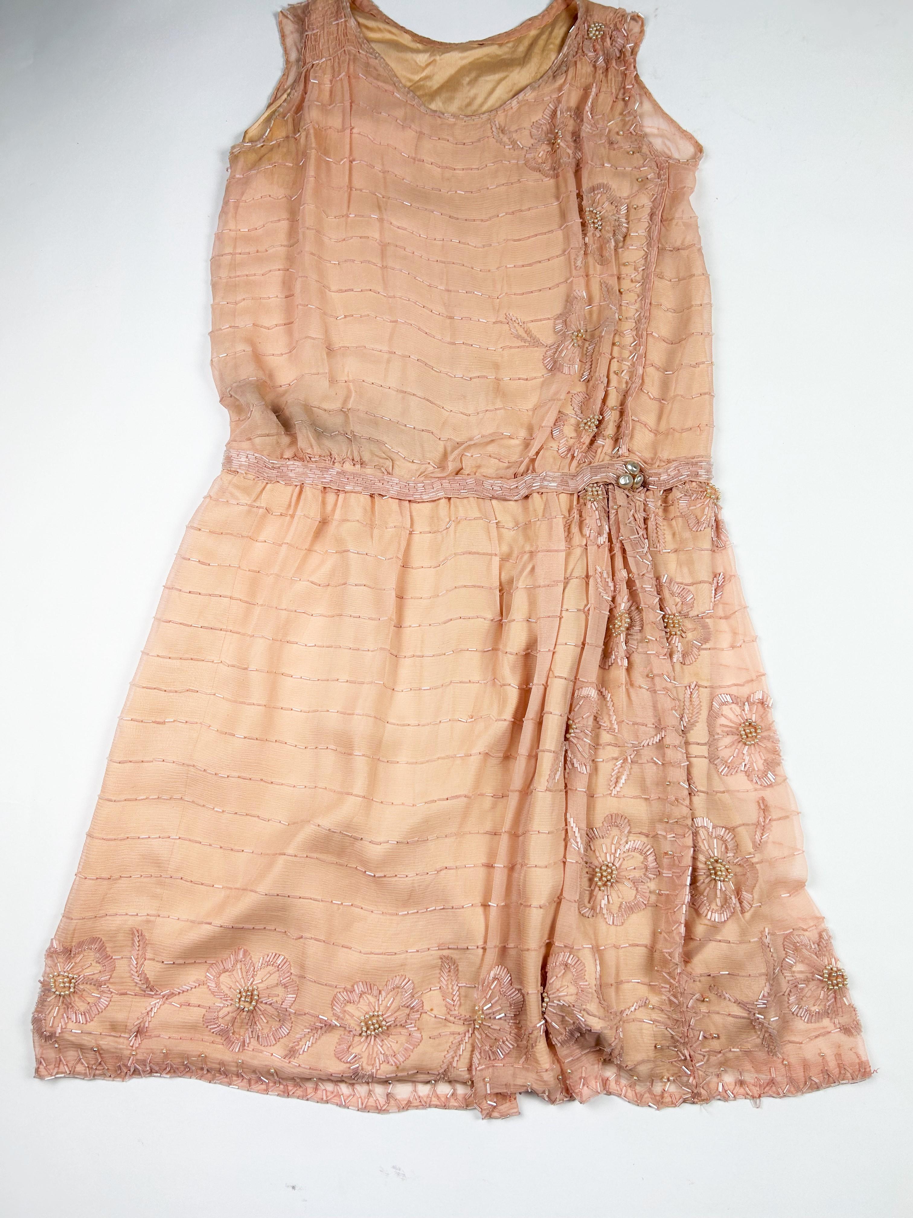 Circa 1920-1925 France
Nice Art Deco ball gown or ceremonial dress in pale salmon pink silk crepe entirely embroidered with tubular glass beads and pearls. Straight sleeveless cut with an asymmetrical blousant effect on the hips punctuated by a belt