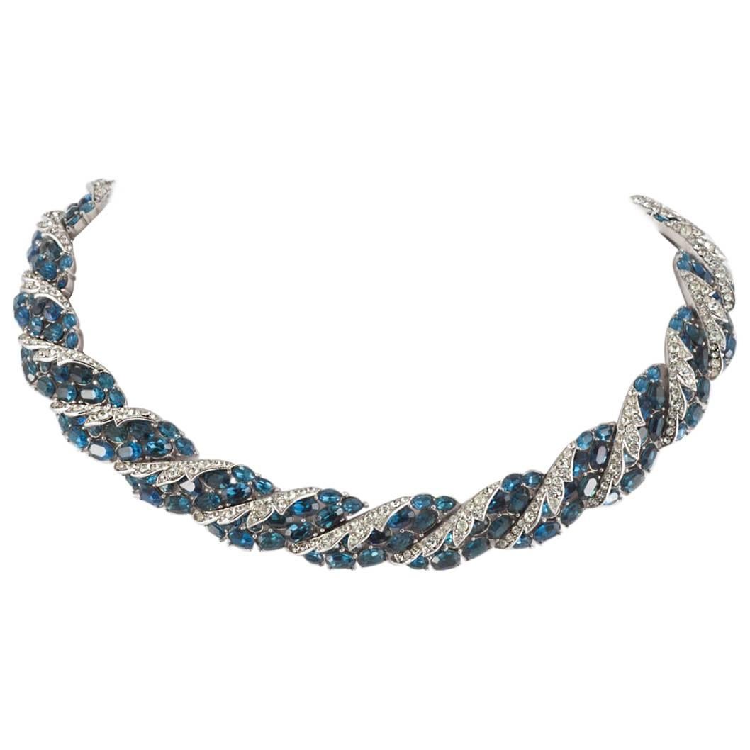 A very beautiful and classic necklace, with matching earrings, designed by Alfred Philippe for Trifari, compromising various sizes of oval cut sapphire pastes, set with clear pastes in rhodium metal. The design is a very stylised floral motif, with