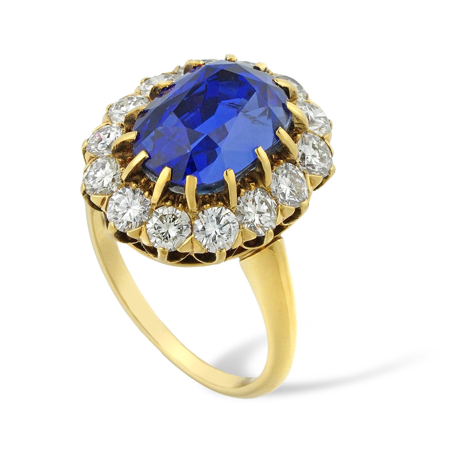 A sapphire and diamond cluster ring, the oval faceted sapphire weighing 8.32 carats, accompanied by GCS Report stating to be of Sri Lankan origin with no indications of heating, surrounded by fourteen round brilliant-cut diamonds estimated to weigh